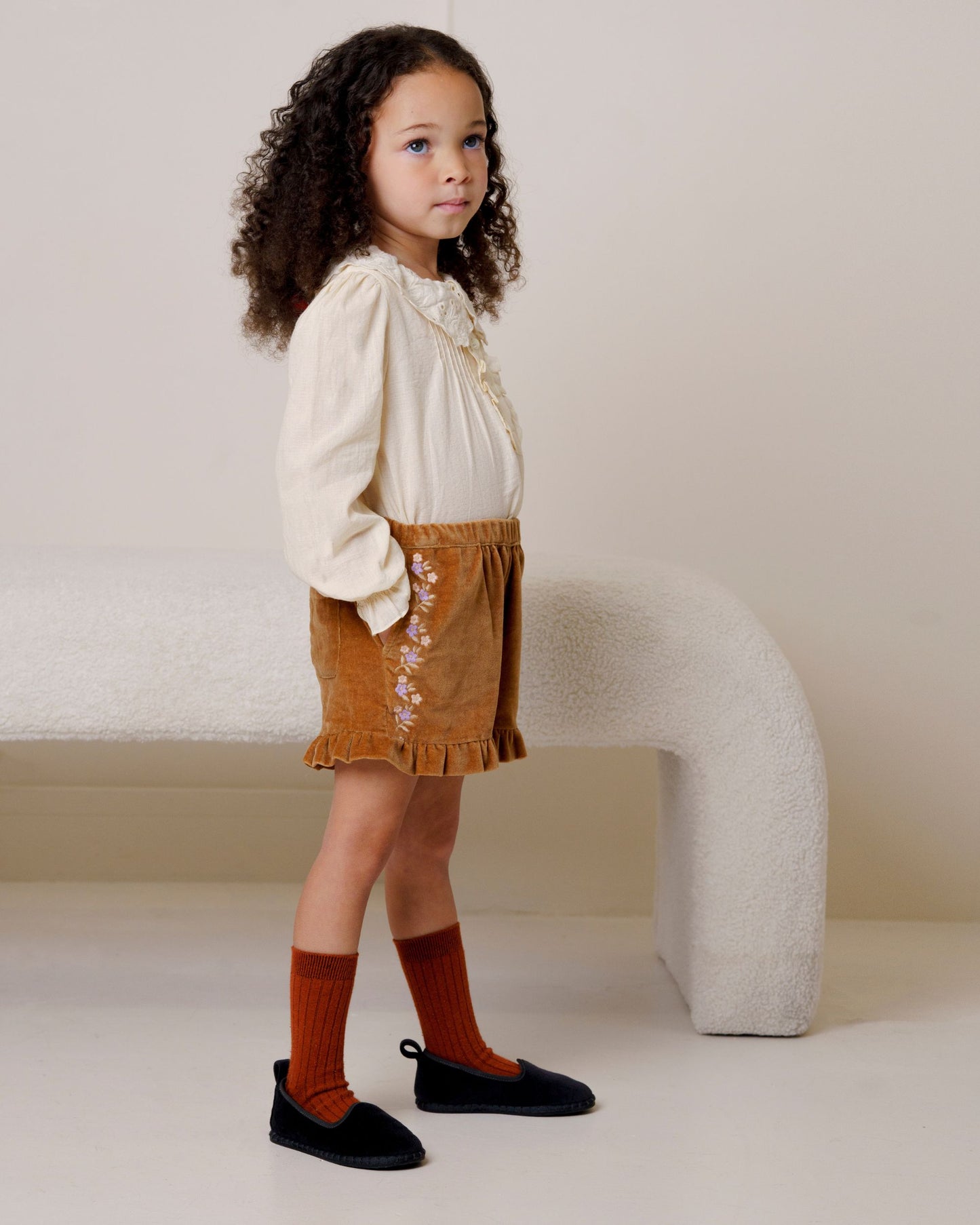 Early Sunday, Joseph Short Dungaree in Almond, made from Dyed Cotton Velvet fabric, featuring Softly structured short dungaree with classic detailing for a vintage-inspired look, shown in a side view of model wearing it