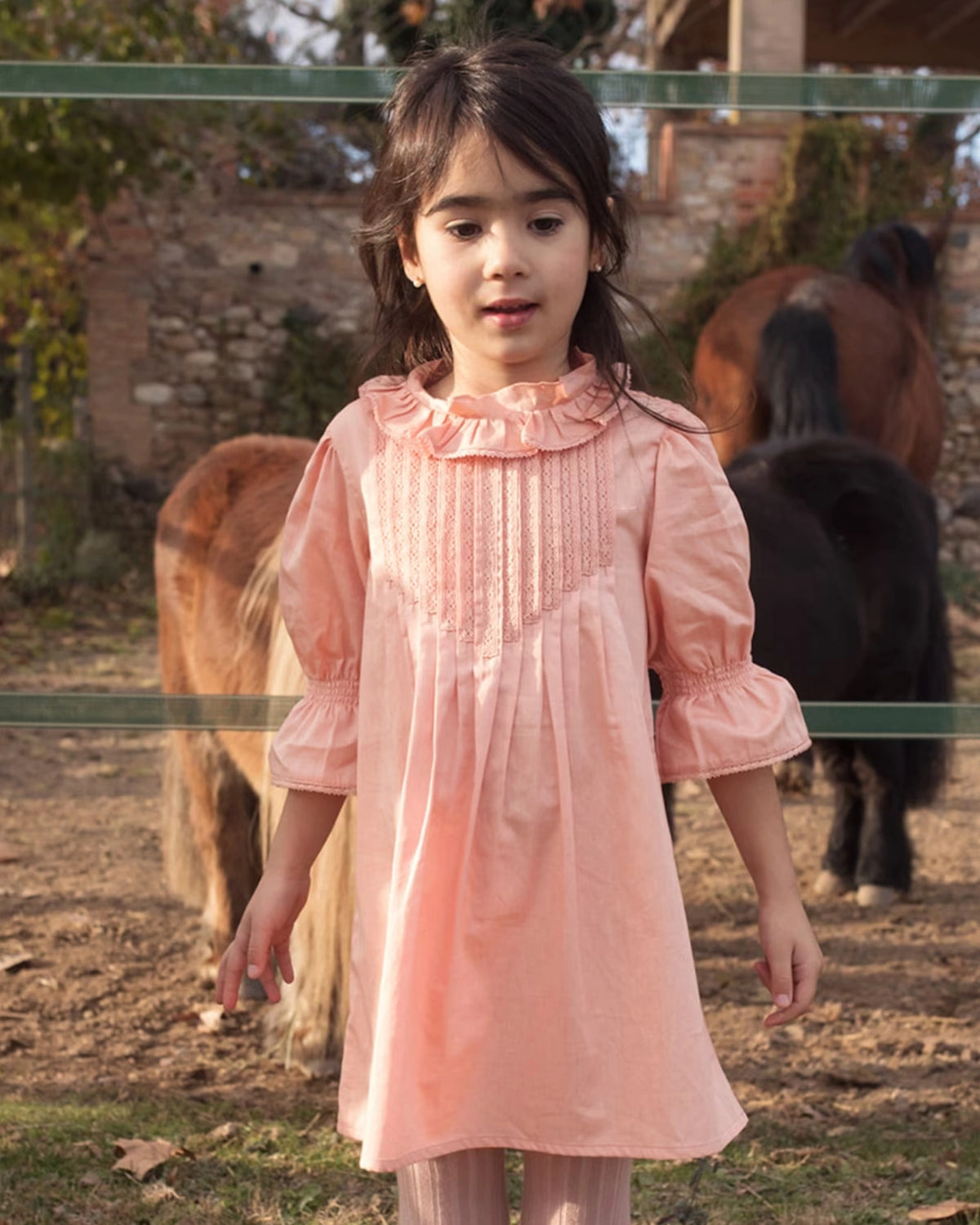 Early Sunday, Julie Dress in Blush Pink, made from Cotton Satin fabric, featuring cute floral embroidery on a Peter Pan collar with a smocked chest, shown in a front view of model wearing it