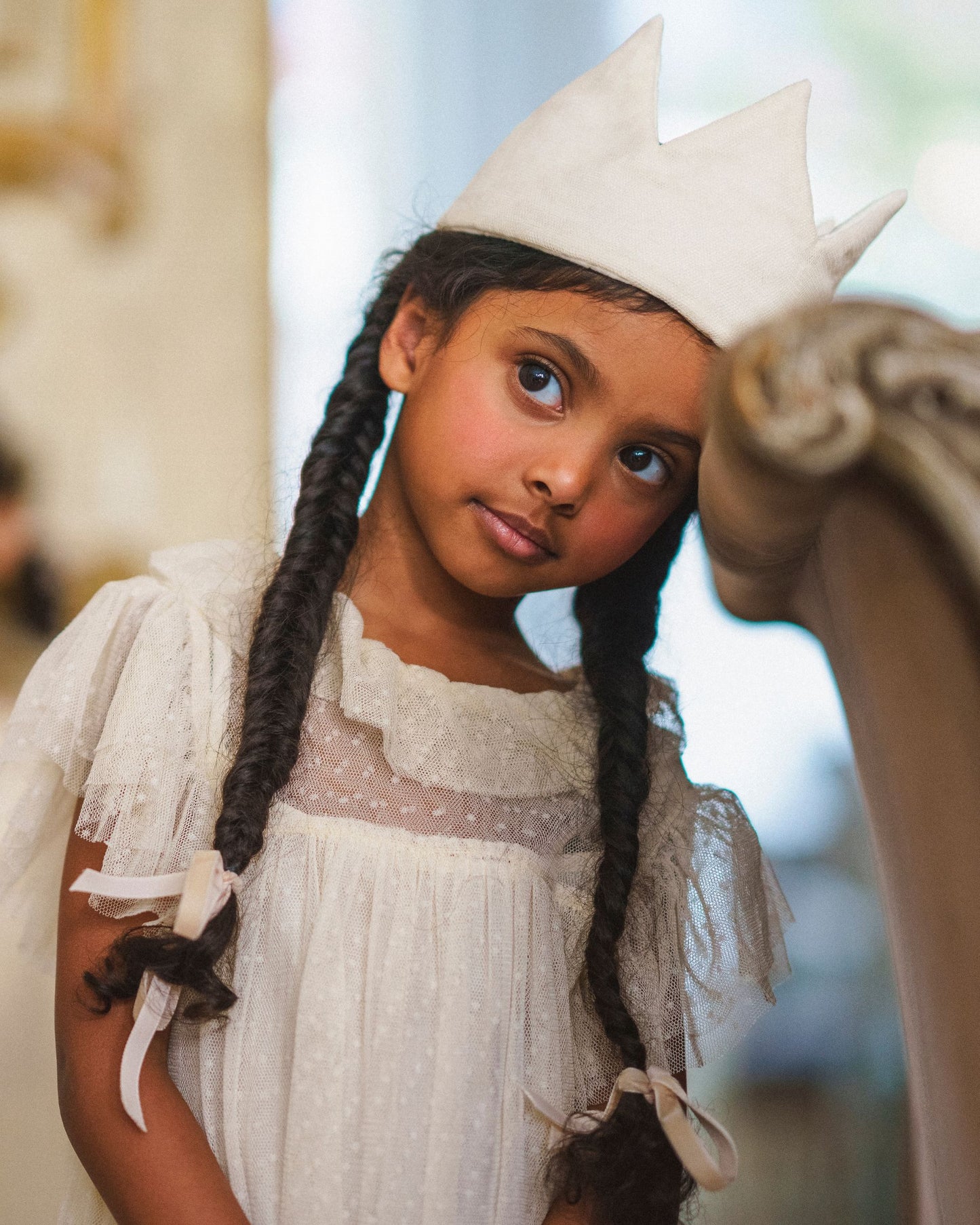 Early Sunday, Kids Crown in Hazelnut Cream Nylon Mesh, made from Dyed Nylon Mesh Dobby fabric, featuring a design with pointed tips & an elasticated band, shown in a close up shot of model wearing it