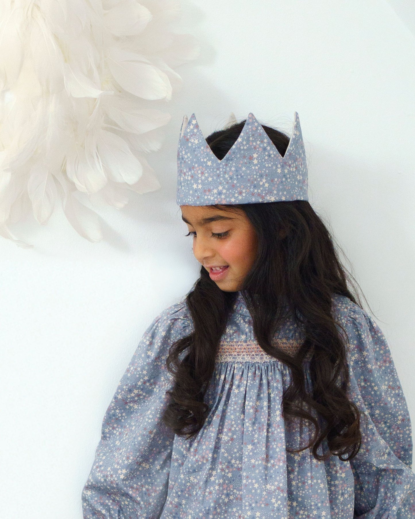 Early Sunday, Kids Crown in Celestial print, made from Printed 60s Cotton Satin fabric, featuring a design with pointed tips & an elasticated band, shown in a front view of model wearing it