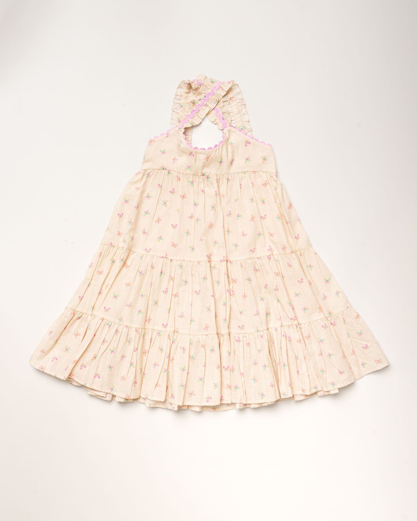 Early Sunday, Laura Dress in Butterfly Print color, made from printed cotton tiny swiss dobby fabric, featuring Crisscross ruffle straps with delicate trim accents and a softly gathered tiered skirt, shown in a front flat-lay view