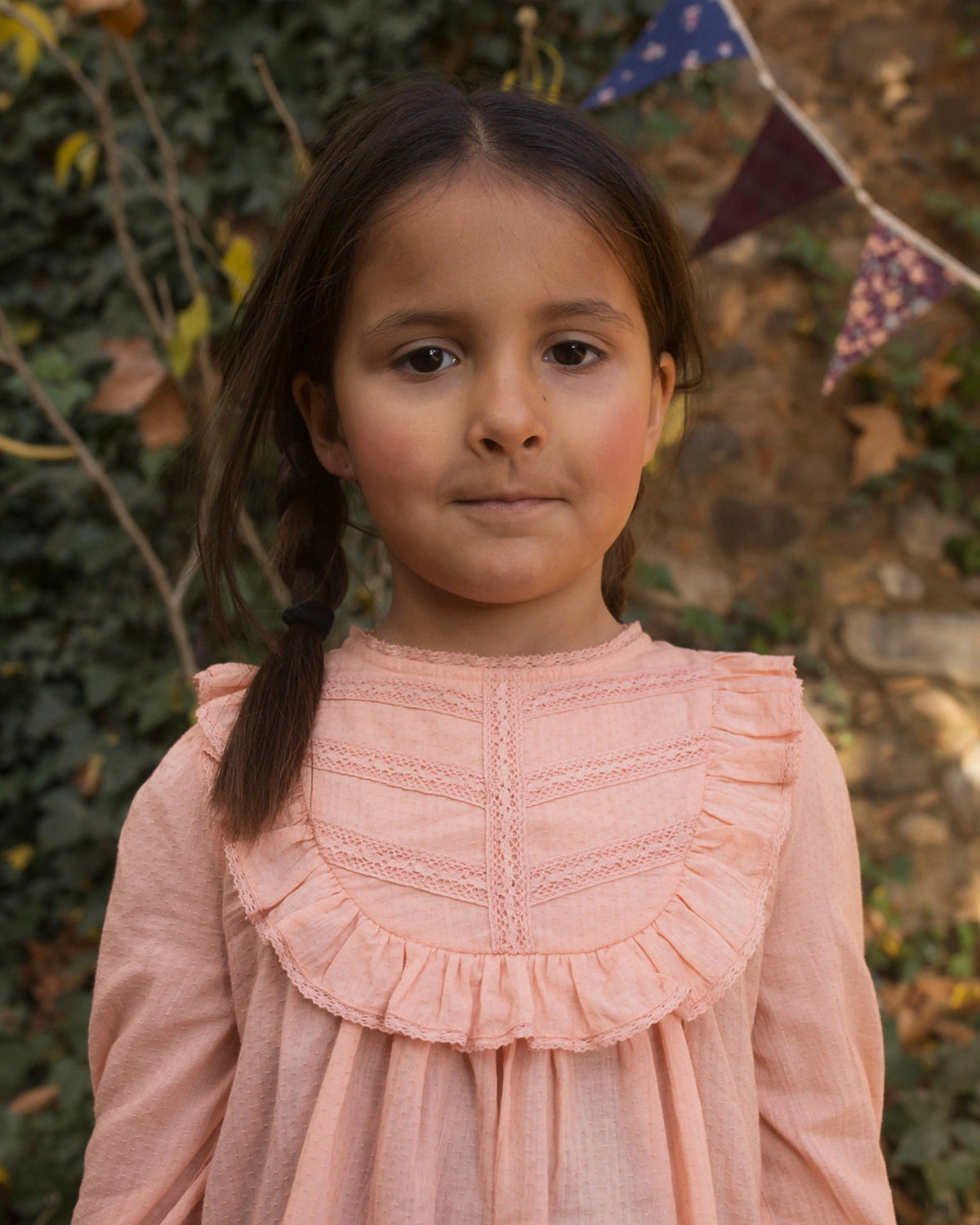 Early Sunday, Lauren Blouse in Blush, made from Cotton Jeera Dobby Voile fabric, featuring layered lace-trimmed ruffles and delicate pintuck detailing on the yoke, shown in a close up shot of model wearing outdoors