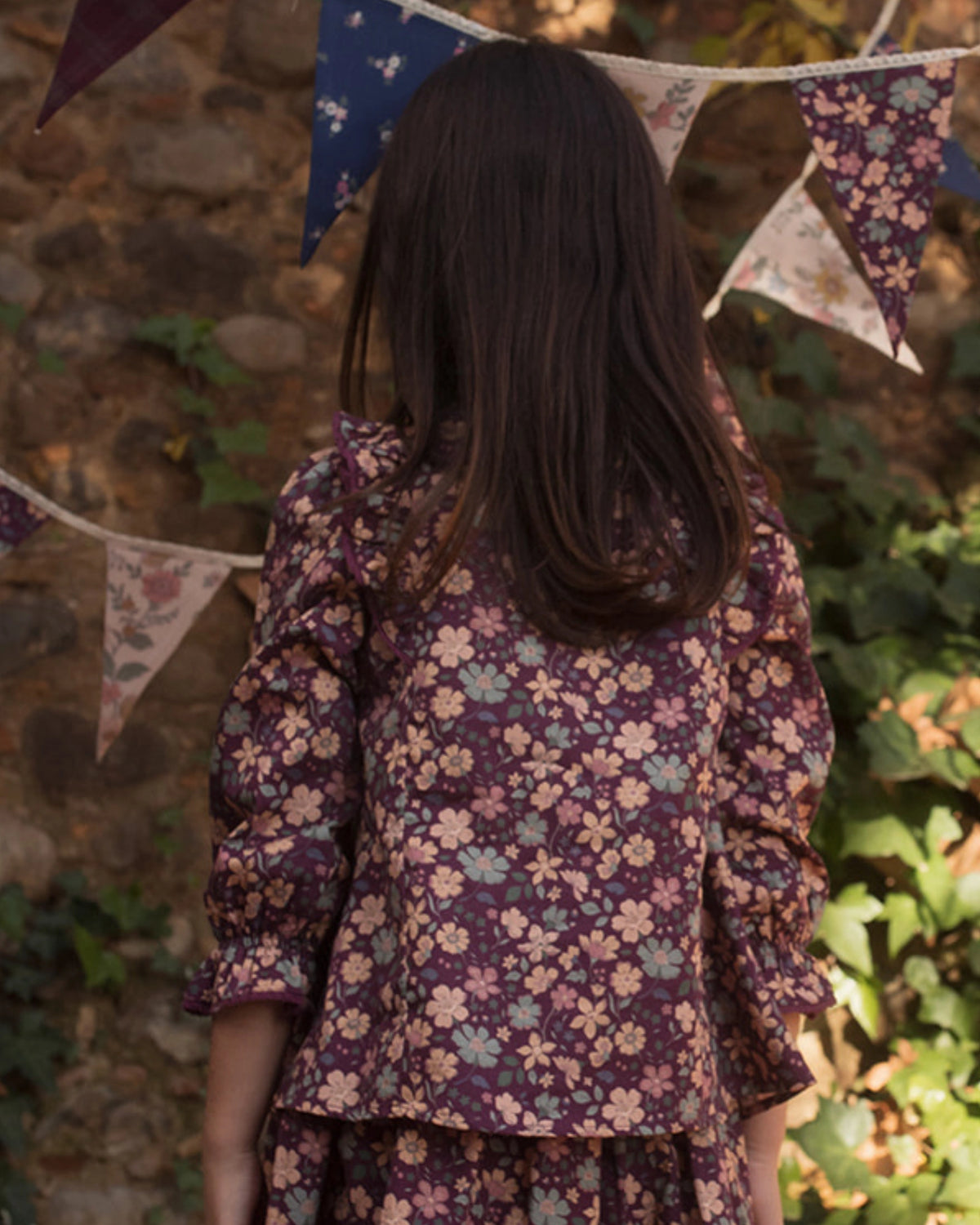 Early Sunday, Lauren Blouse in Plum, made from Printed Cotton Satin fabric, featuring layered lace-trimmed ruffles and delicate pintuck detailing on the yoke, shown in a back view of model wearing it