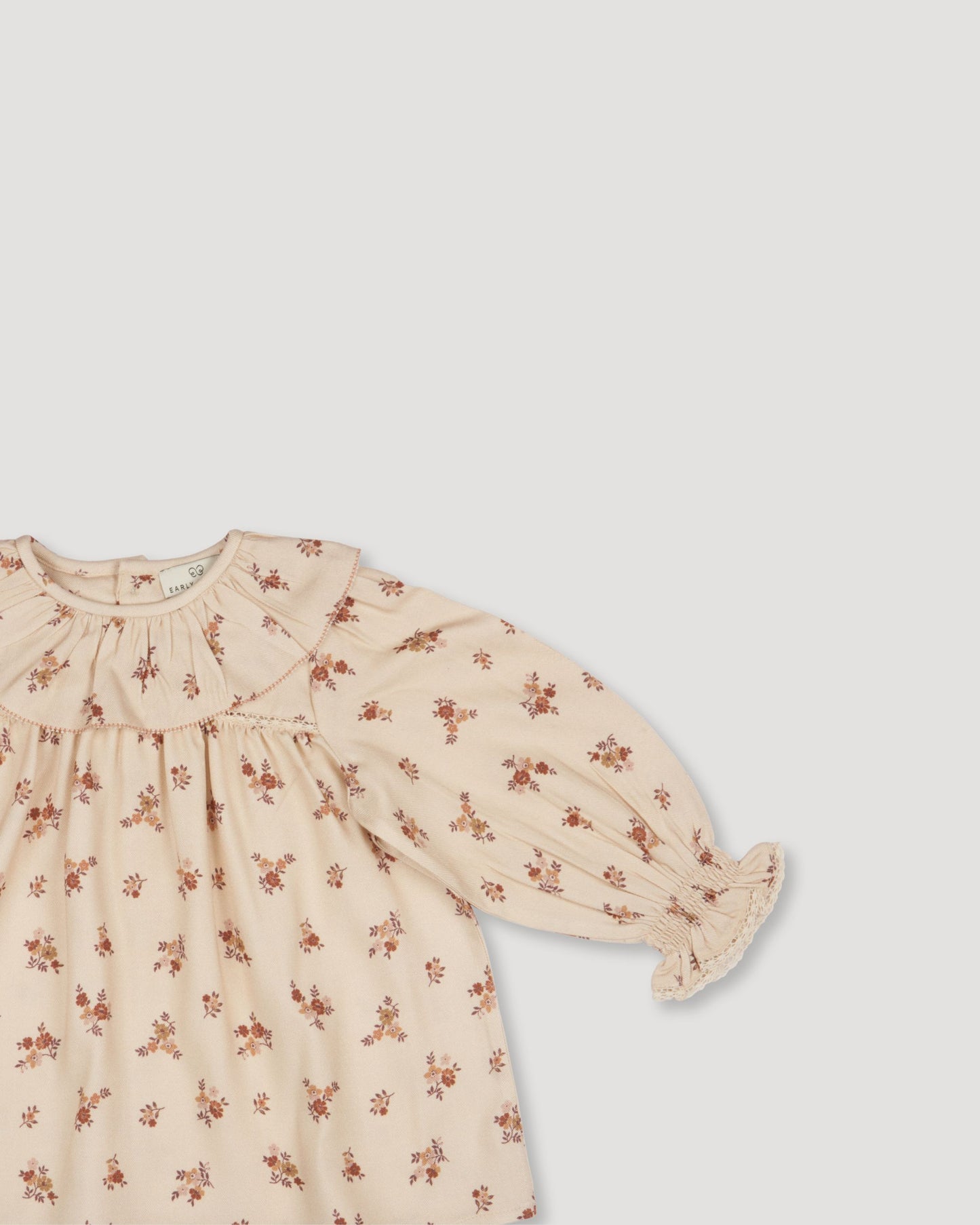 Early Sunday, Libby Baby Dress & Bloomer Set in Ditsy Bouquet Cream print color, made from Printed Viscose Rayon Twill fabric, featuring long sleeves with frilly neck & floral print, shown in a closeup flat-lay view