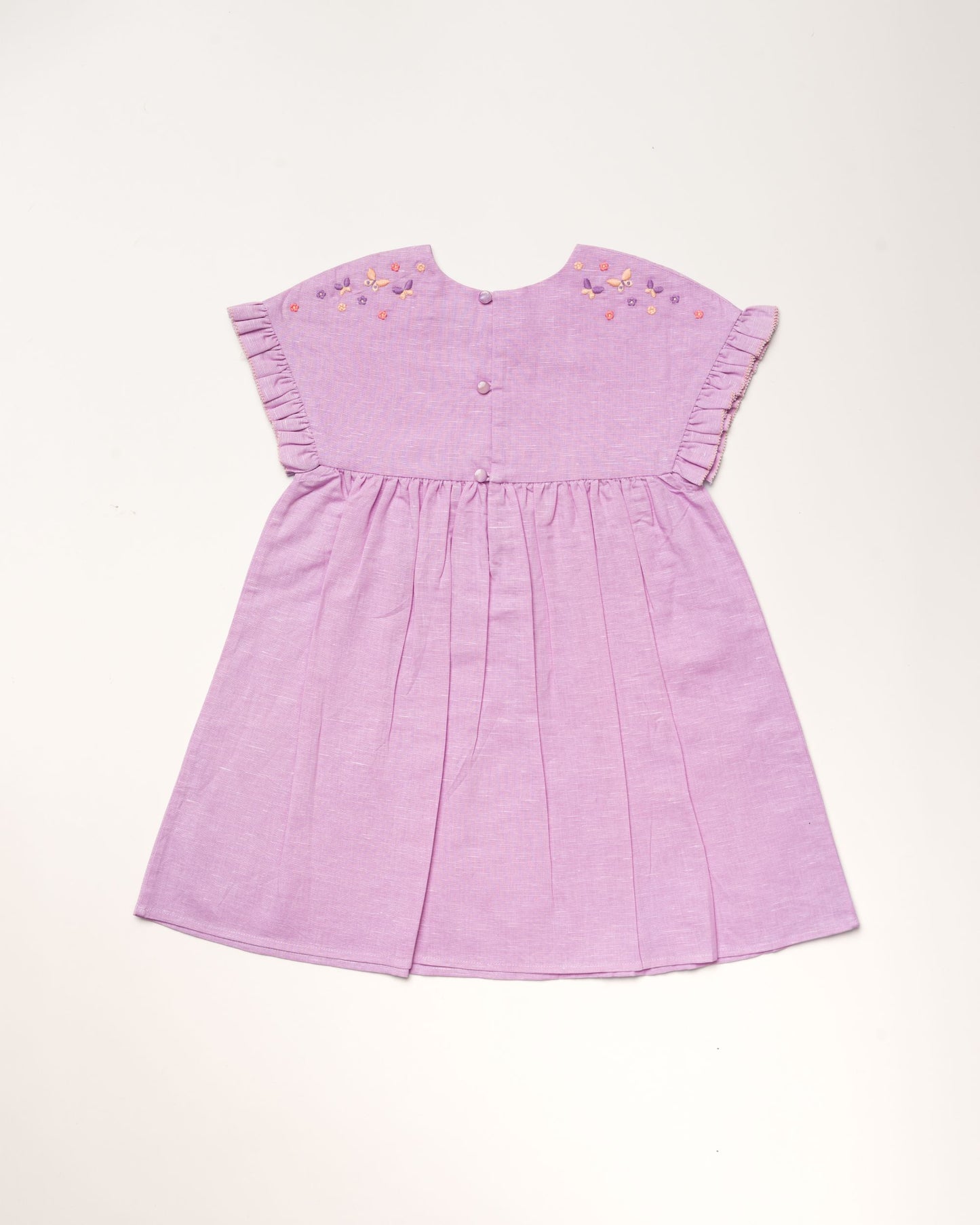 Early Sunday, Lila Dress in Lilac color, made from 70% cotton 30% linen solid fabric, featuring Scalloped neckline with contrast stitching, flutter sleeves, gentle gathers, and embroidered hem detail, shown in a back flat-lay view