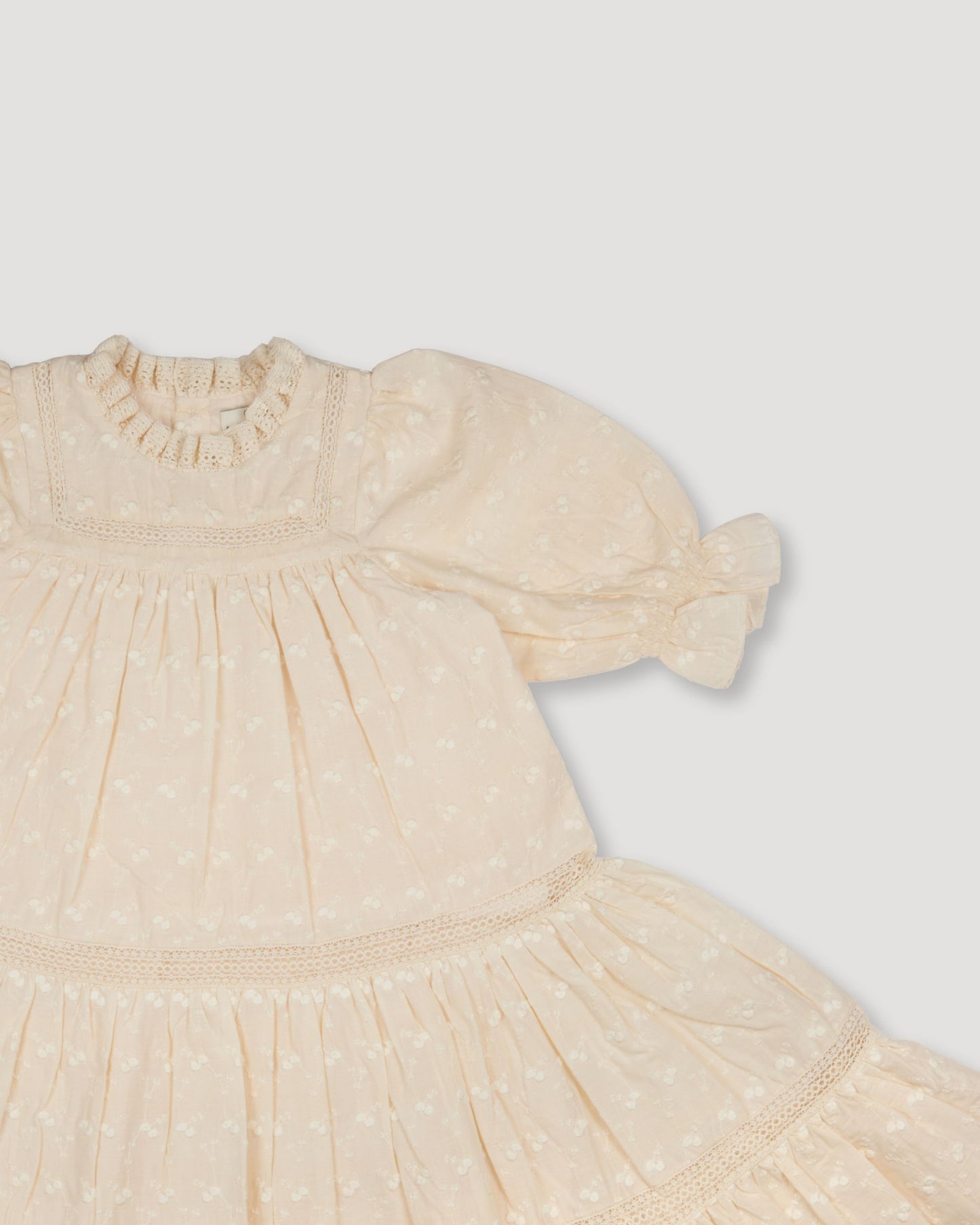 Early Sunday, Lilly Dress in Hazelnut Cream, made from All-Over Embroidered Cotton Cambric fabric, featuring Delicate floral embroidery placed softly across the dress for a timeless, heirloom-inspired finish, shown in a closeup flat-lay view
