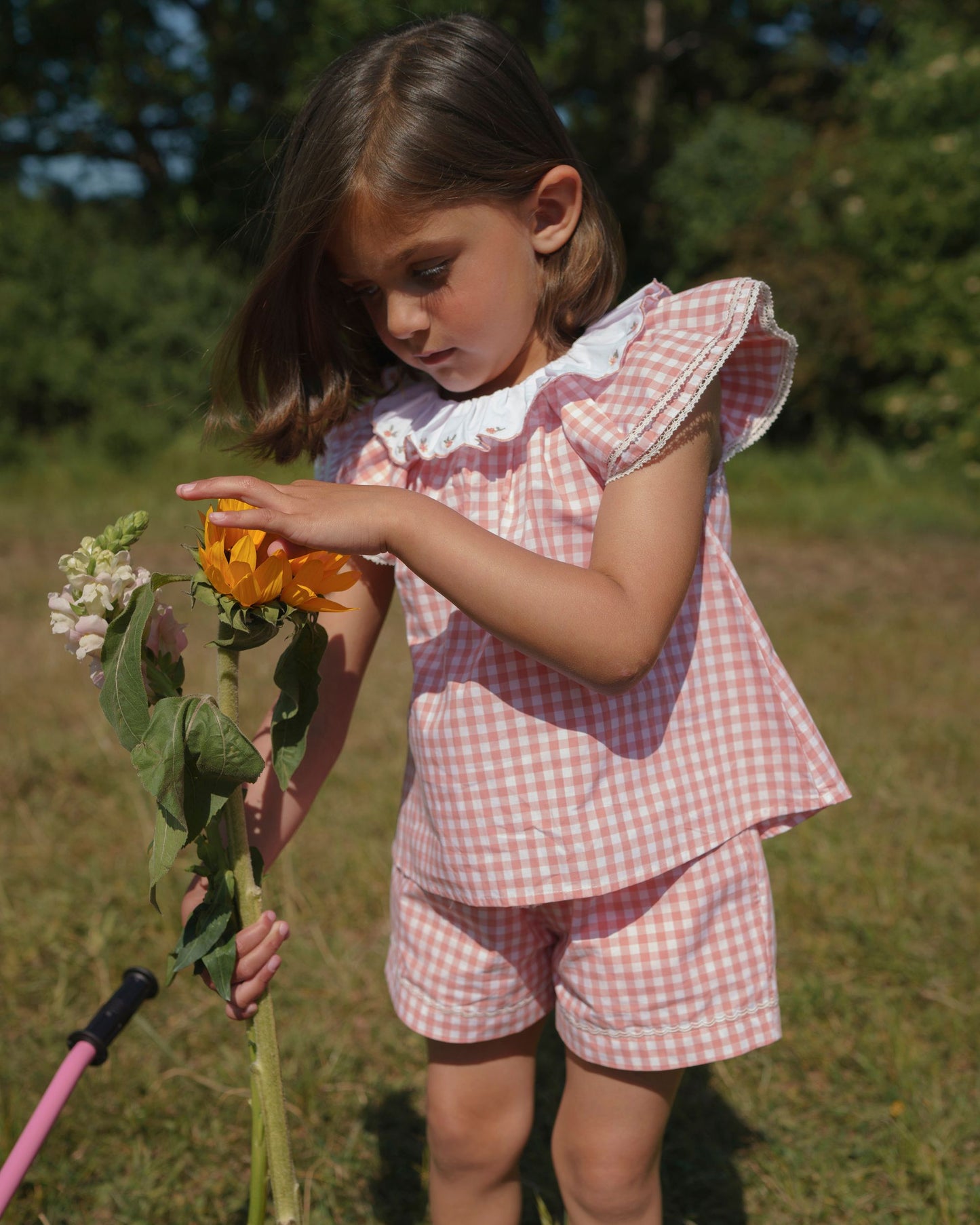 Early Sunday, Lola Blouse in Peony color, made from 100% cotton gingham checks fabric, featuring Ruffled neckline, flutter sleeves with contrast detailing, and gentle gathers for a sweet silhouette, shown in a model in motion