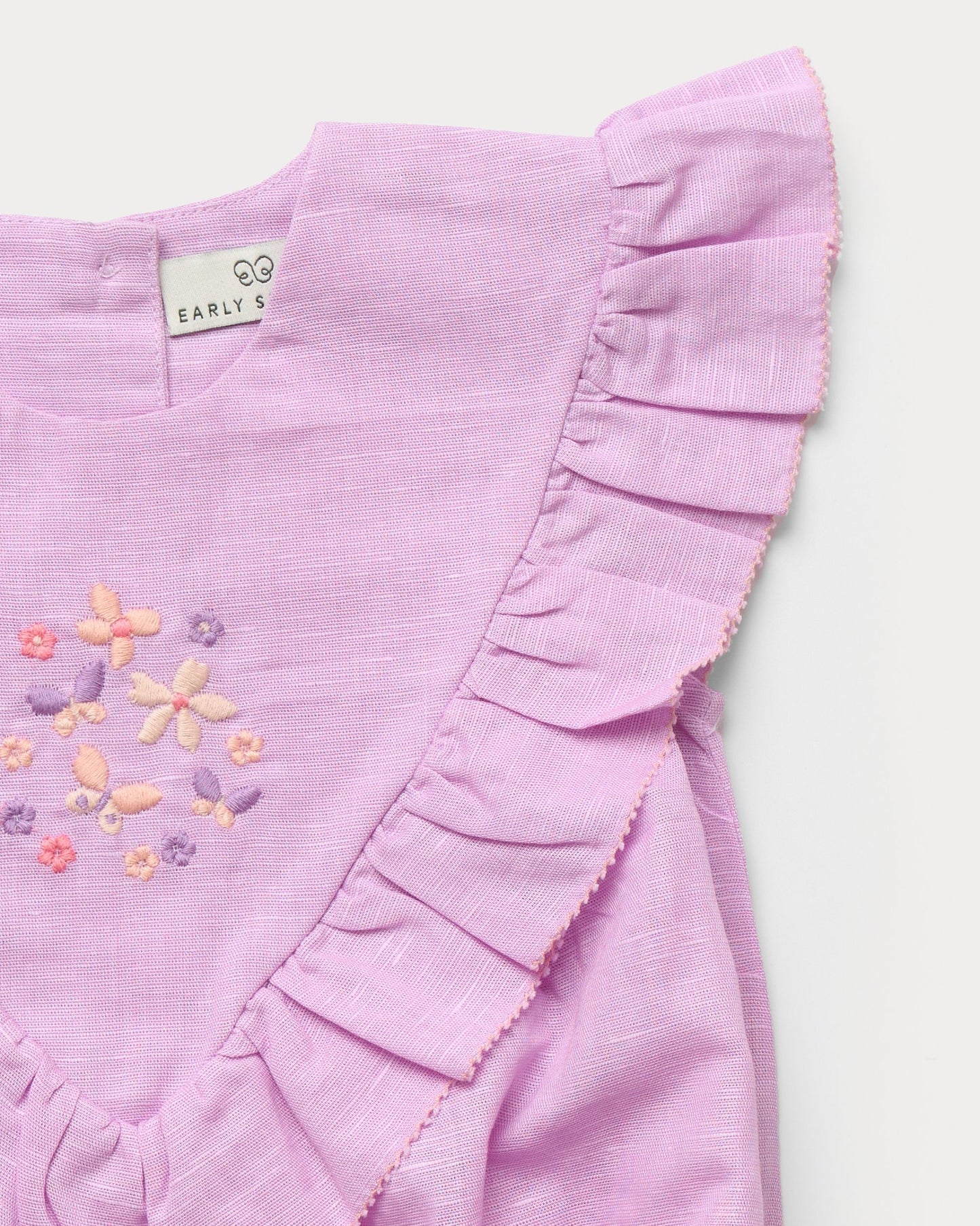 Early Sunday, Lucy Baby Bubble Romper in Lilac color, made from 70% Cotton 30% Linen fabric, featuring a bubble pattern with beautiful embroidery, shown in a closeup flat-lay view
