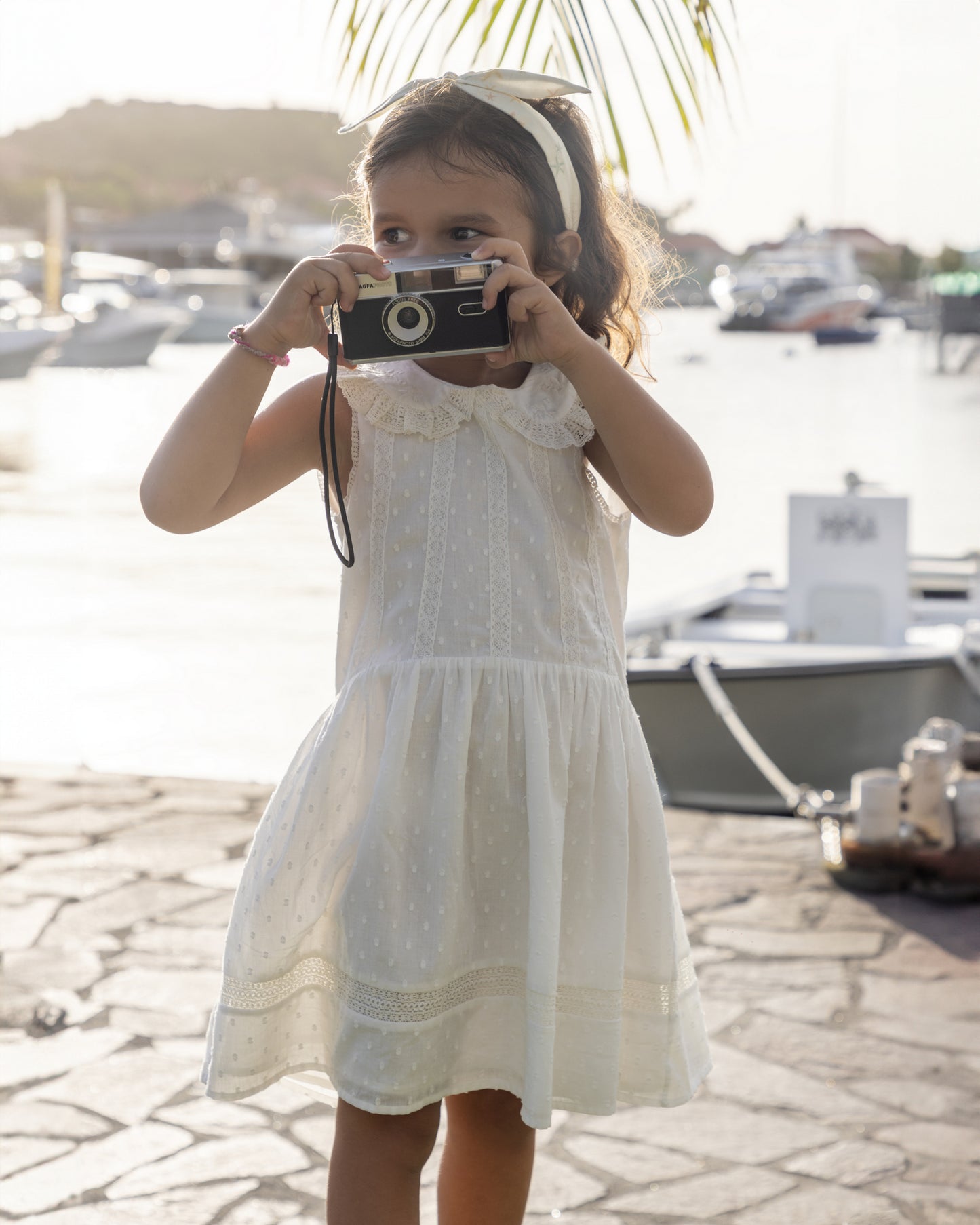 Early Sunday, LYS Dress in Ivory color, made from Cotton Dobby Swiss Dots fabric, featuring flattering fit with delicate finishes, combining style and functionality for an effortlessly elegant look, shown in a front view of model wearing outdoors