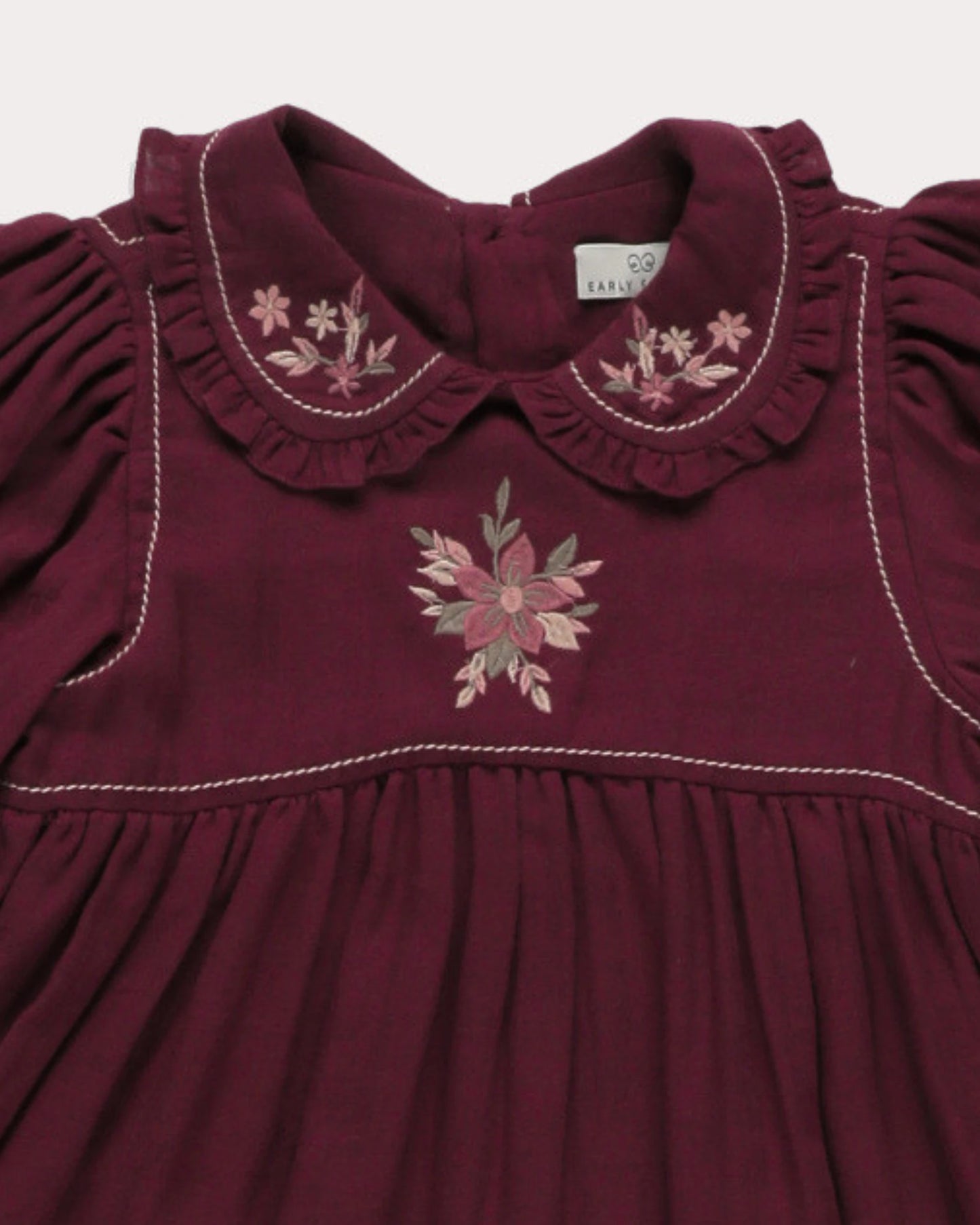 Early Sunday, Marguerite Dress in Plum, made from Cotton Double Gauze fabric, featuring floral embroidery with frilled Peter Pan collar, shown in a closeup flat-lay view