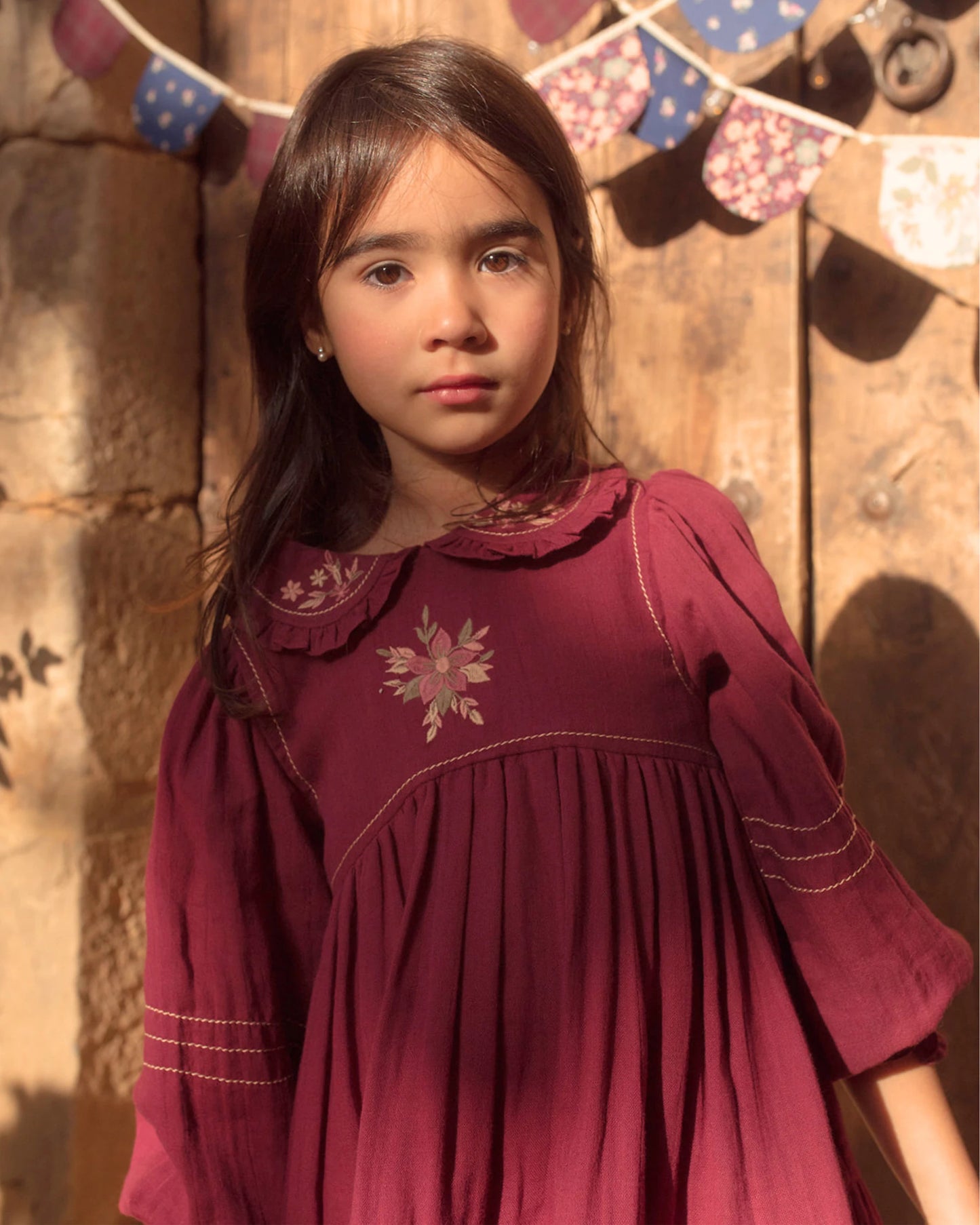 Early Sunday, Marguerite Dress in Plum, made from Cotton Double Gauze fabric, featuring floral embroidery with frilled Peter Pan collar, shown in a close up shot of model wearing it
