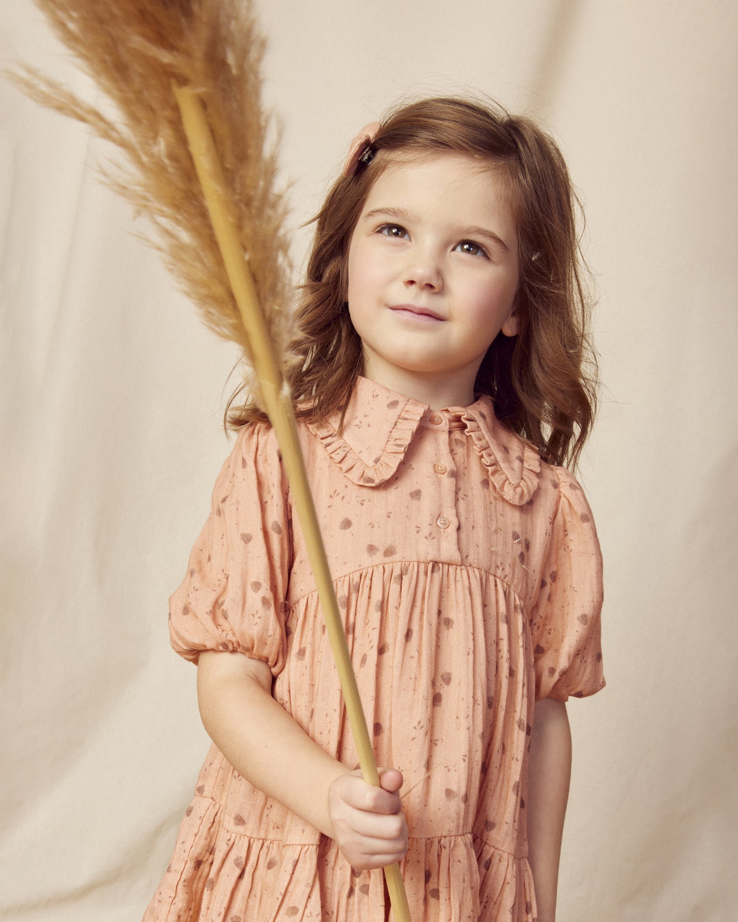 Early Sunday, Marguerite Dress in Acorn Dusty Pink, made from Printed Cotton Double Gauze fabric, featuring classic silhouette with a collar and ruffle detailing, shown in a front view of a model wearing it in a studio setting