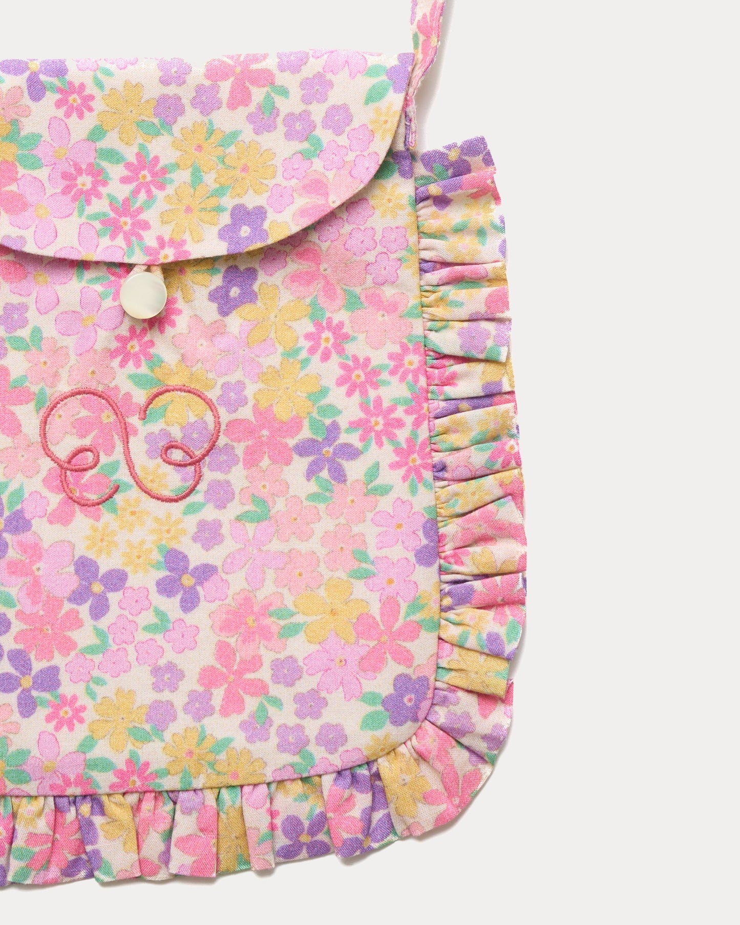Early Sunday, Miss Sunday Sling in Emma Floral Purple color, made from Organic Printed Cotton Cambric fabric, featuring a frill detailed sling purse with flap closure, shown in closeup flat-lay view