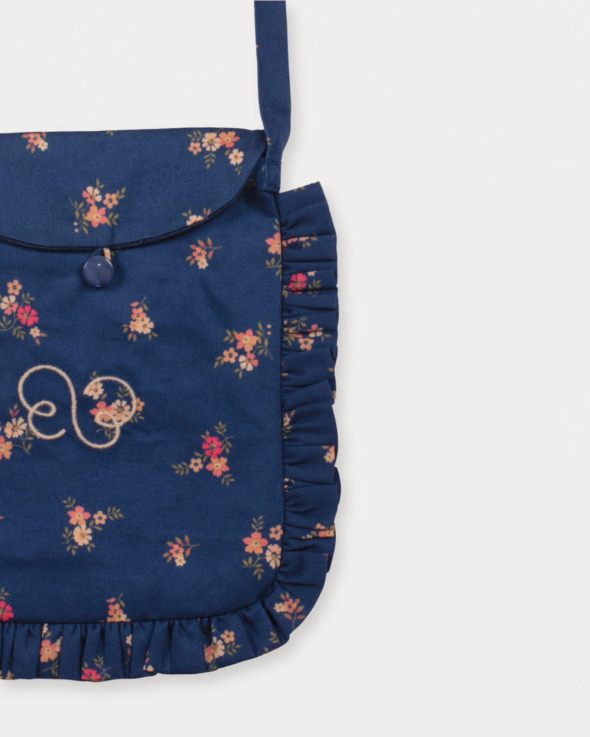 Early Sunday, Miss Sunday Sling in Ditsy Bouquet Navy Blue, made from Printed Cotton Satin fabric, featuring a frill detailed sling purse with flap closure, shown in a closeup flat-lay view