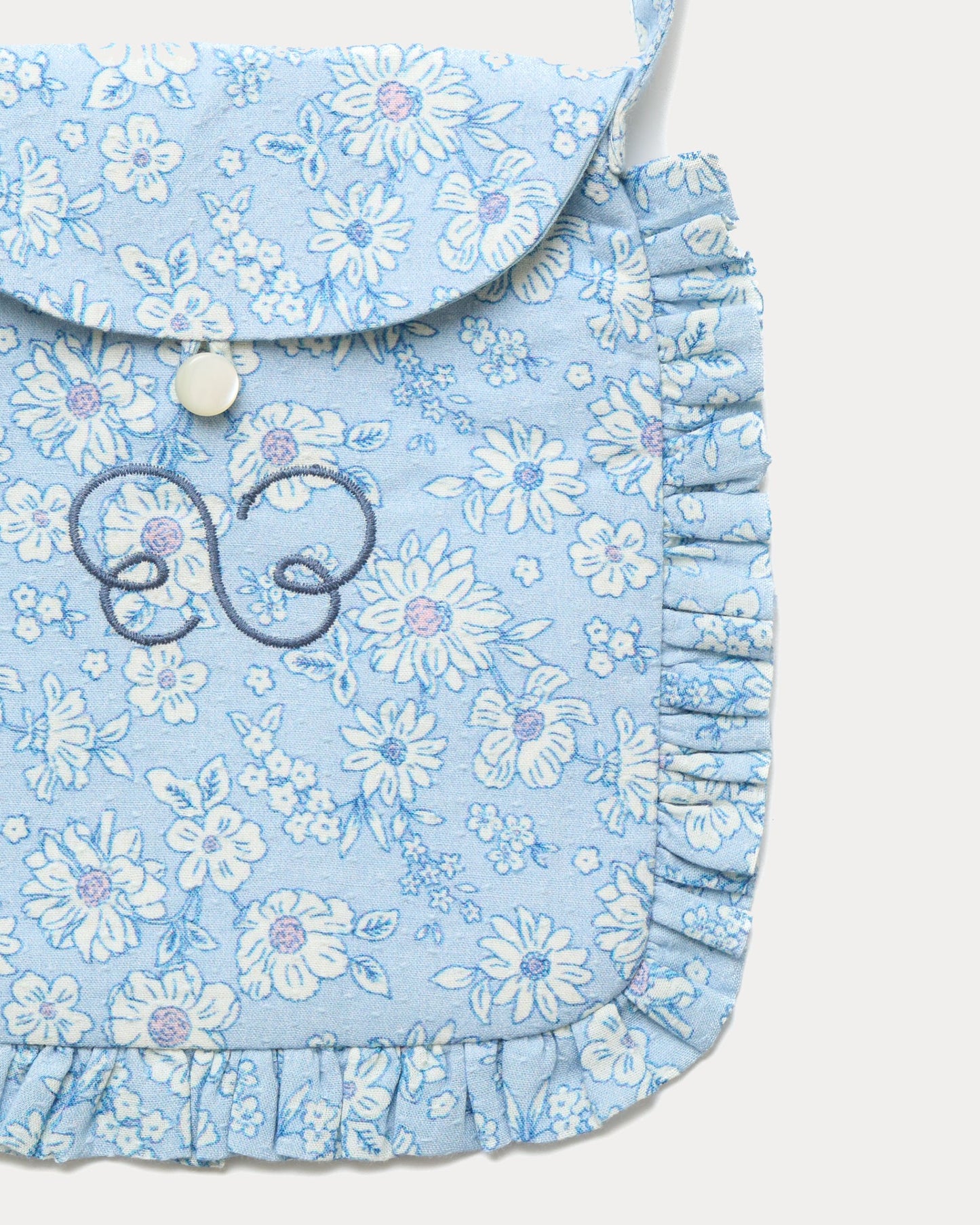Early Sunday, Miss Sunday Sling in Tonal Floral Blue color, made from Printed Cotton Tiny Swiss Dobby fabric, featuring a frill detailed sling purse with flap closure, shown in closeup flat-lay view