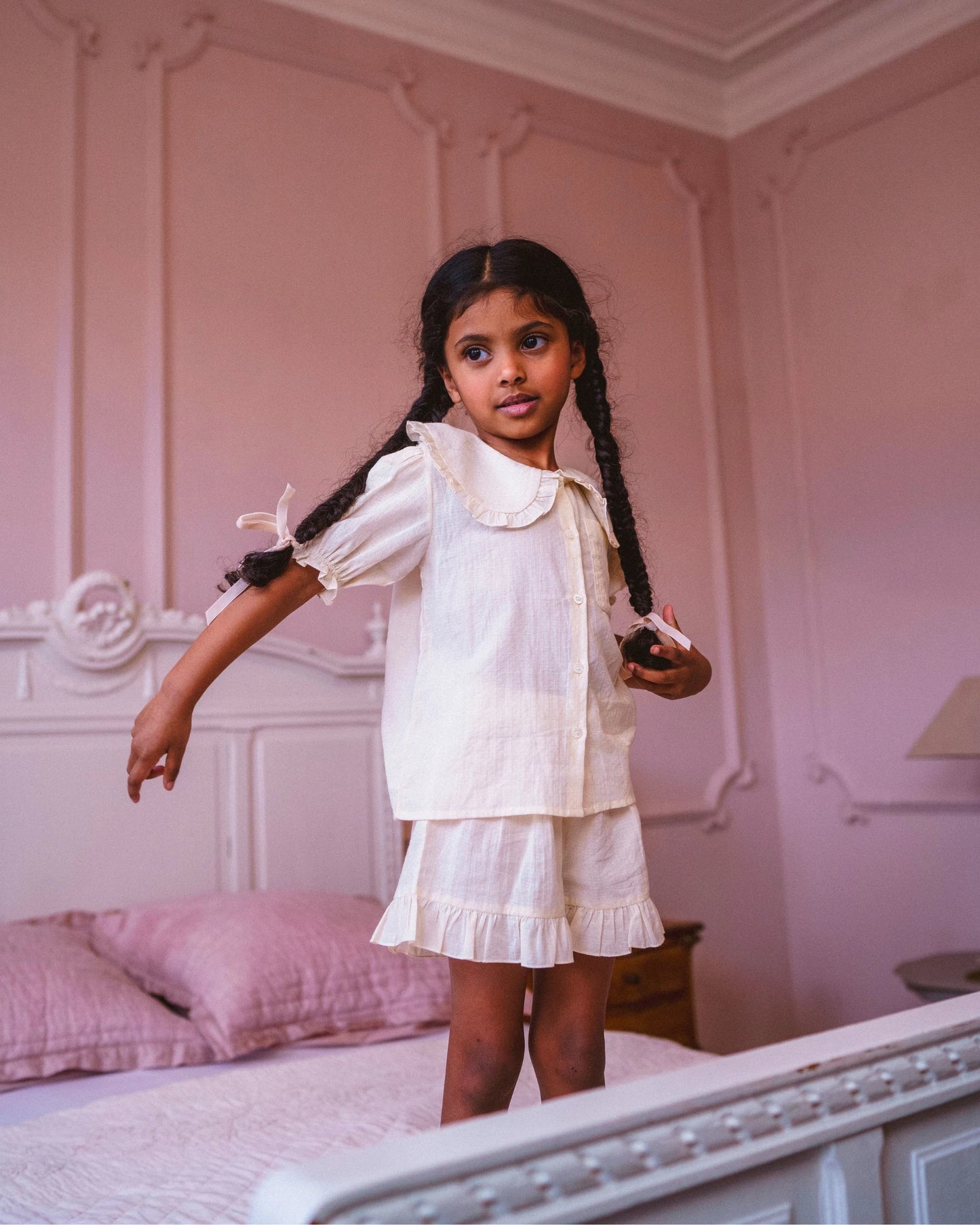 Early Sunday, Peggy Pyjama Set in Hazelnut Cream, made from Dyed Cotton Swiss Dobby Tiny Dots fabric, featuring Button-down shirt with classic tailoring, subtle gathers, and gentle volume, shown in a front view of a model wearing it in a studio setting