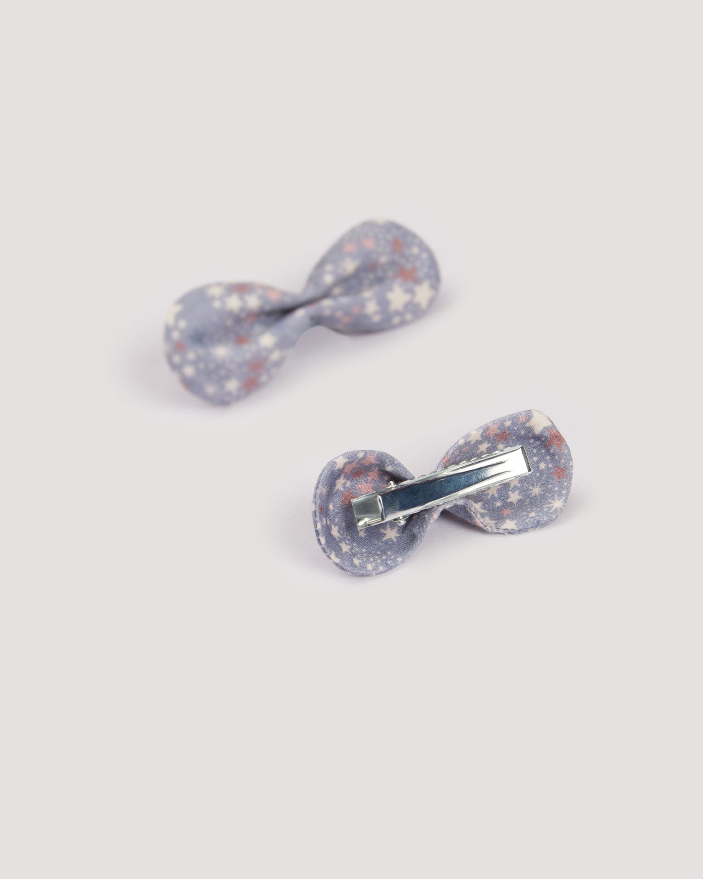 Early Sunday, Penelope Clip in Celestial print, made from Printed 60s Cotton Satin fabric, featuring a set of two bow clips with a secure fit, shown in a back flat-lay view