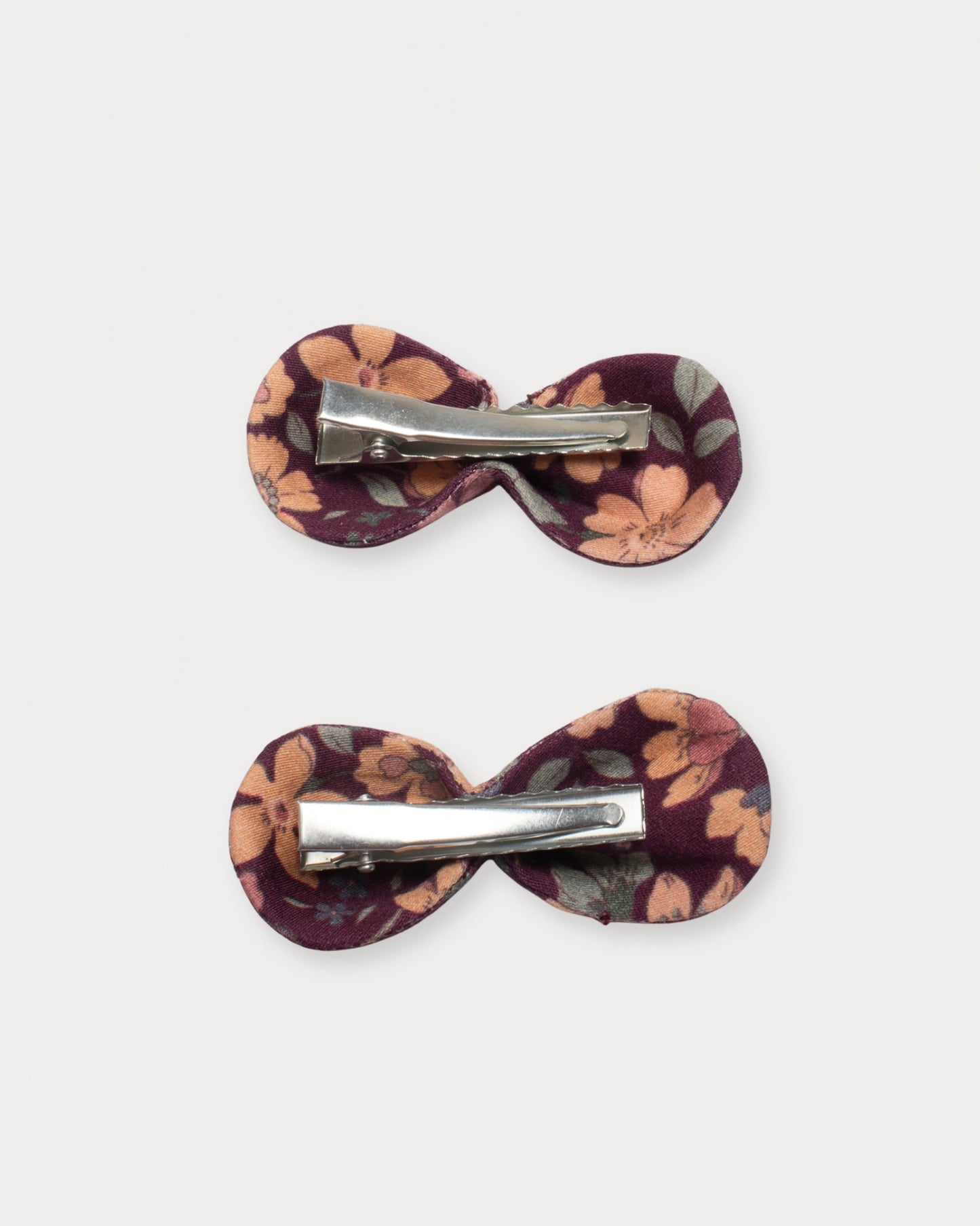 Early Sunday, Penelope Clip in Garden Flowers Plum, made from Printed Cotton Satin fabric, featuring a set of two bow clips with a secure fit, shown in a back flat-lay view