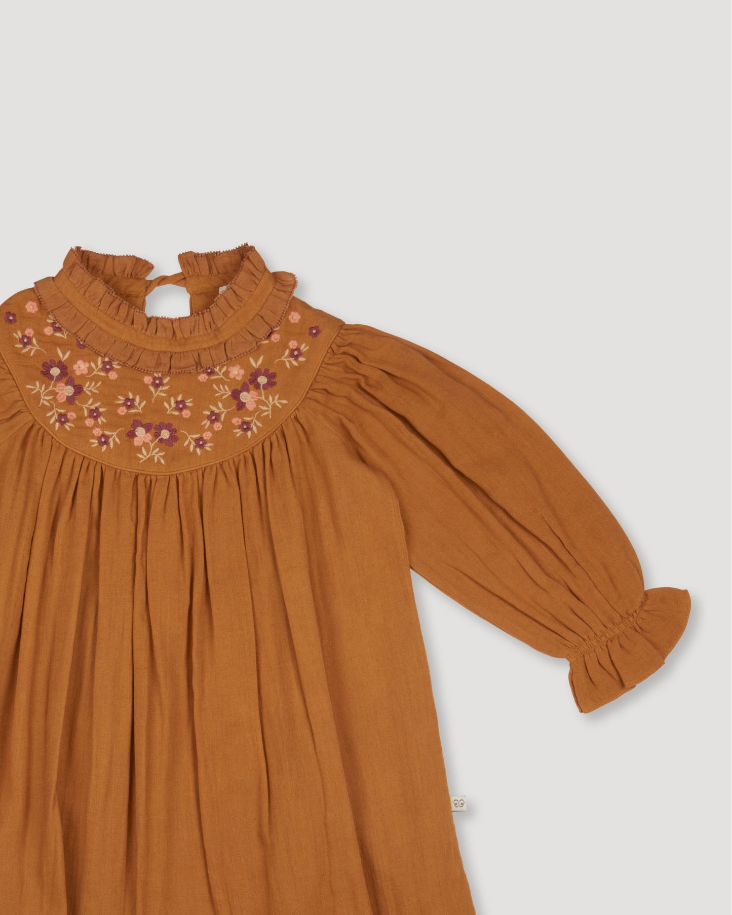 Early Sunday, Penelope Dress in Almond, made from Dyed Cotton Double Gauze fabric, featuring Hand-embroidered floral motifs, shown in a closeup flat-lay view