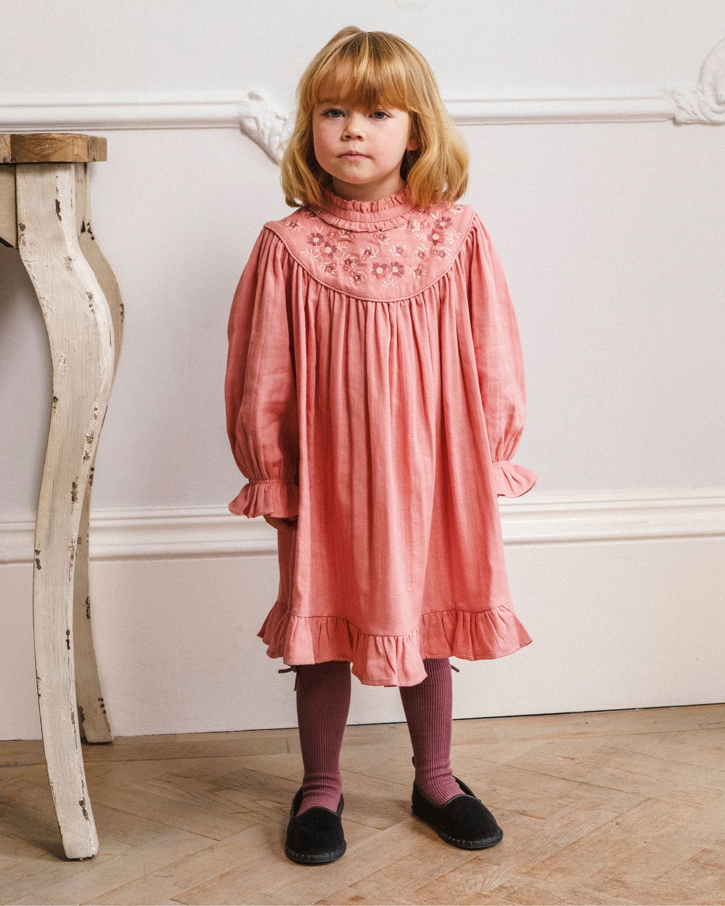 Early Sunday, Penelope Dress in Rose, made from Dyed Cotton Double Gauze fabric, featuring Hand-embroidered floral motifs, shown in a front view of a model wearing it in a studio setting