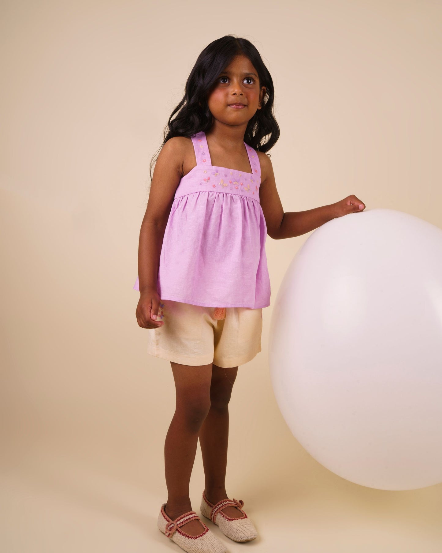 Early Sunday, Roman Short in Sand color, made from 70% Cotton 30% Linen fabric, featuring a relaxed fit with an elastic waistband & beautiful embroidery, shown in a front view of a model wearing it in a studio setting