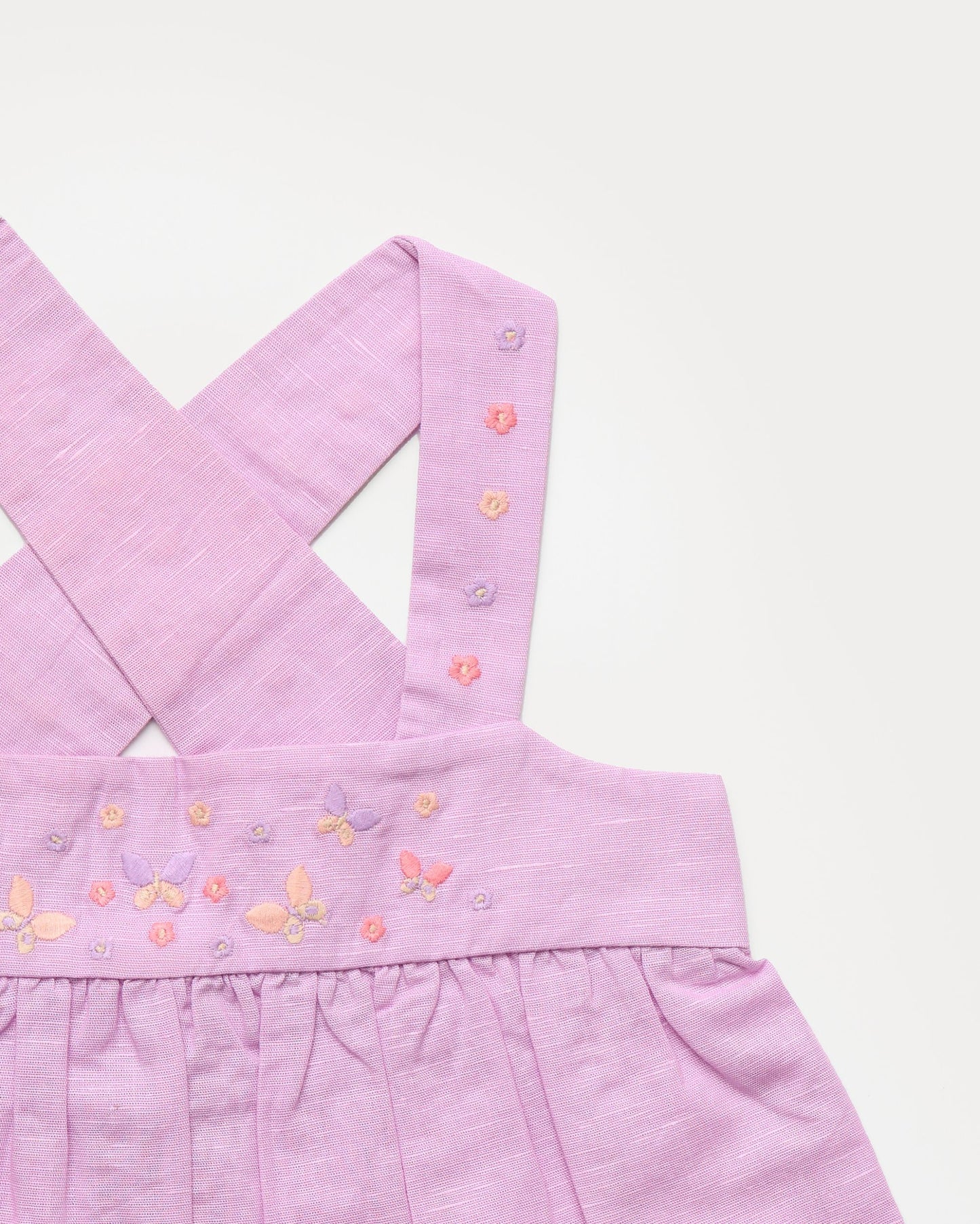 Early Sunday, Romy Blouse in Lilac color, made from 70% Cotton 30% Linen fabric, featuring a sleeveless design with cross-back straps, a gathered waist & a beautiful embroidery, shown in a closeup flat-lay view