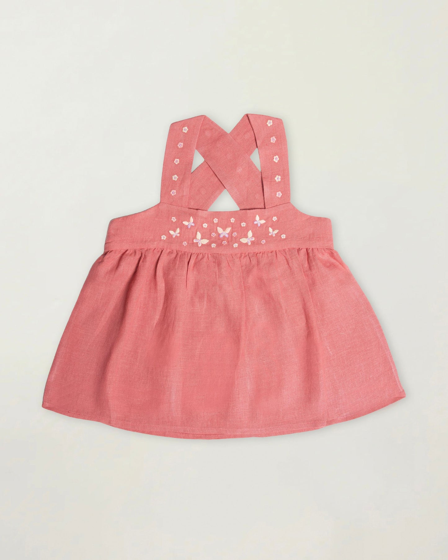 Early Sunday, Romy Blouse in Peony color, made from 70% Cotton 30% Linen fabric, featuring a sleeveless design with cross-back straps, a gathered waist & a beautiful embroidery, shown in a front flat-lay view