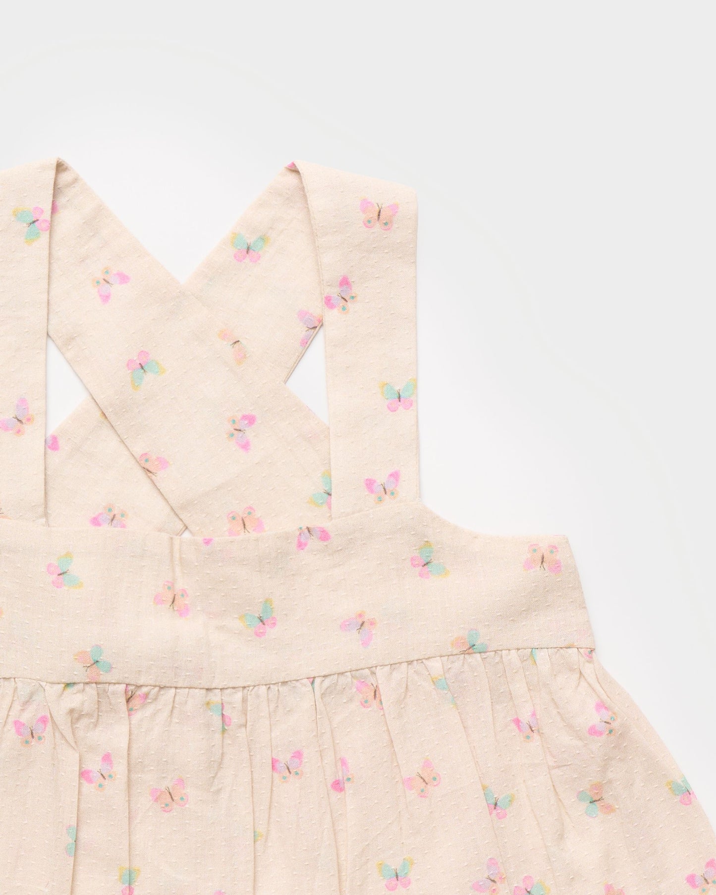 Early Sunday, Romy Blouse in Butterflies print, made from Printed Cotton Tiny Swiss Dobby fabric, featuring a sleeveless design with cross-back straps, a gathered waist & a soft flared silhouette, shown in closeup flat-lay view