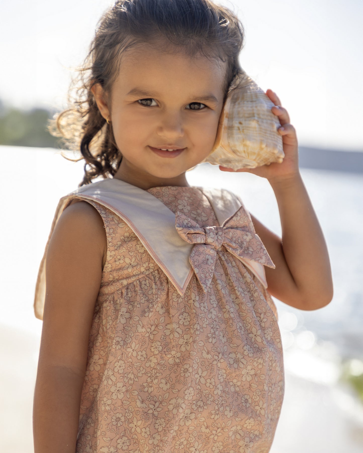 Early Sunday, Sabrina Dress in Garden Flowers print, made from Printed Cotton Cambric fabric, featuring flattering fit with delicate finishes, combining style and functionality for an effortlessly elegant look, shown in a an angled view of a model wearing outdoors