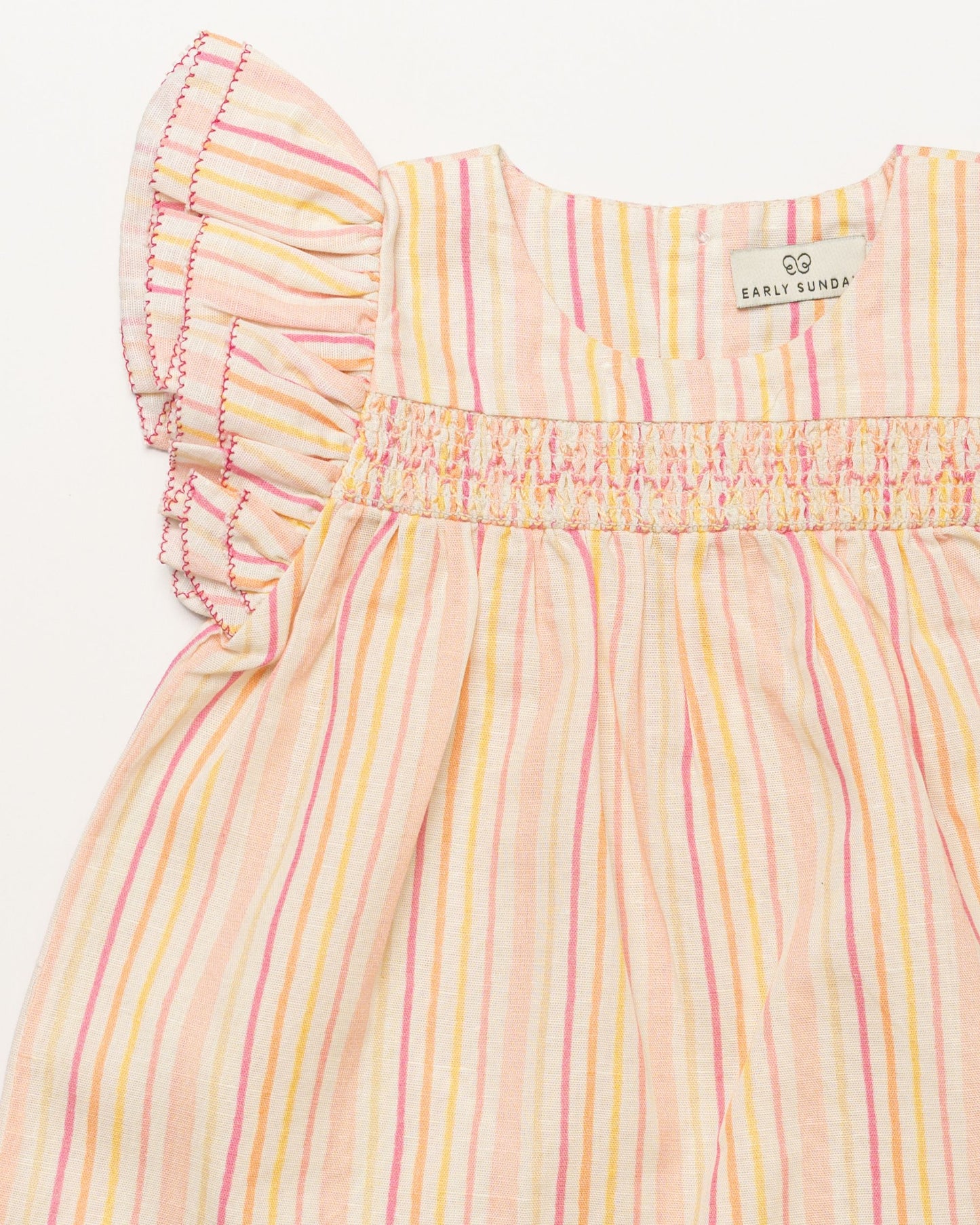 Early Sunday, Sienna Baby Dress & Bloomer Set in Pink Stripes print, made from 70% Cotton 30% Linen fabric, featuring a relaxed fit with smocked chest band & frilled sleeves, shown in a closeup flat-lay view