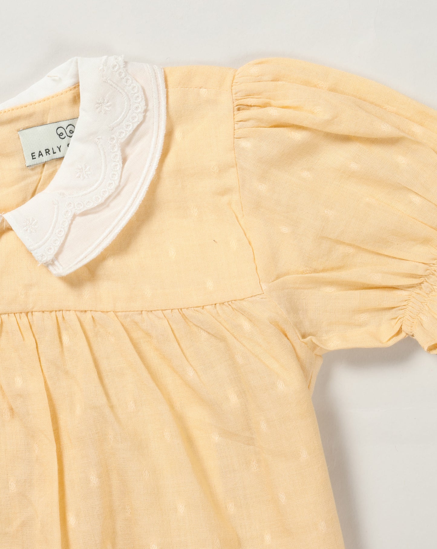 Early Sunday, Sukie Baby Dress & Bloomer in Vanilla color, made from Cotton Dobby Swiss Dots fabric, featuring flared dress with a relaxed fit for ease of movement, matching bloomer with an elasticated waistband for comfort and flexibility., shown in a closeup flat-lay view