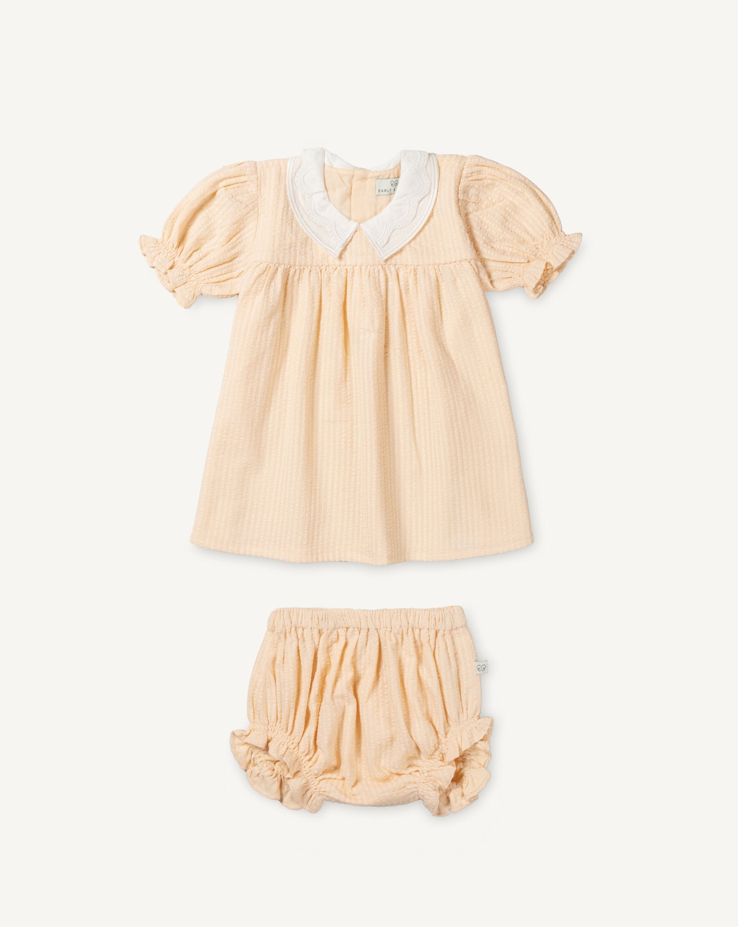 Early Sunday, Sukie Baby Dress & Bloomer in Warm Sand color, made from Cotton Seersucker fabric, featuring flared dress with a relaxed fit for ease of movement, matching bloomer with an elasticated waistband for comfort and flexibility., shown in a front flat-lay view