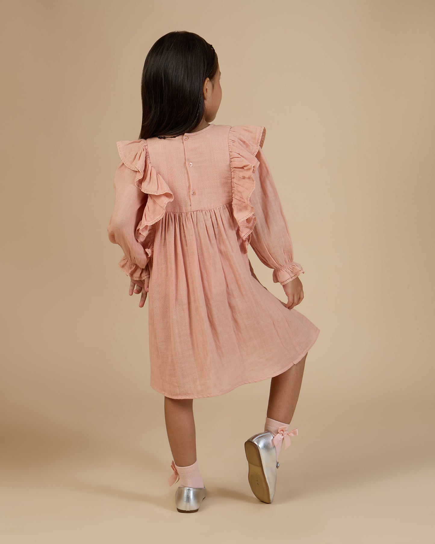 Early Sunday, Suzanne Dress in Dusty Pink, made from Cotton Double Gauze fabric, featuring classic silhouette with floral embroidery around the yoke and ruffle detailing, shown in a back view of model wearing it