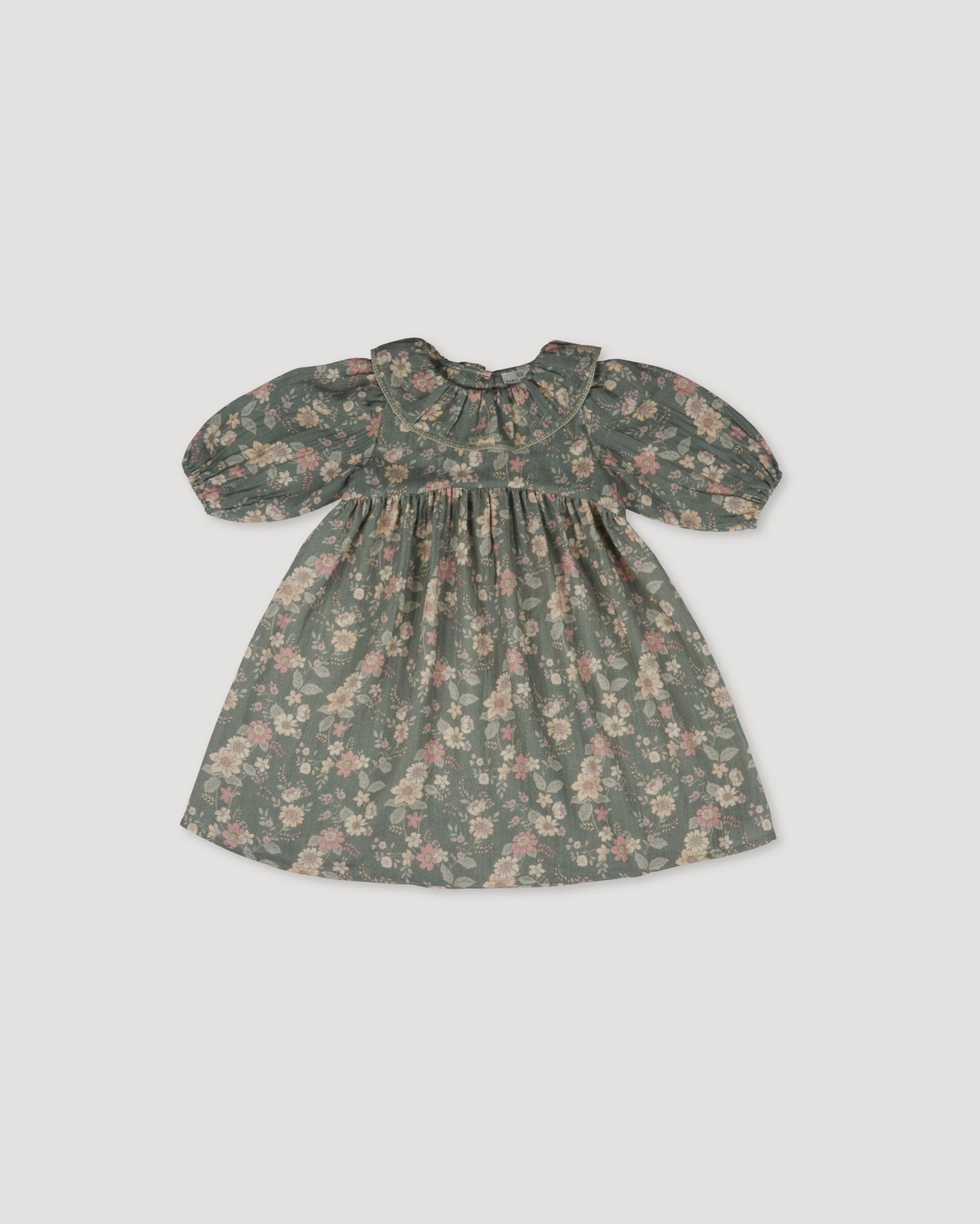 Early Sunday, Suzie Dress in Autumn Bloom Soft Green, made from Printed Cotton Double Gauze fabric, featuring classic silhouette with a ruffle neckline and mother-of-pearl buttons, shown in a back flat-lay view