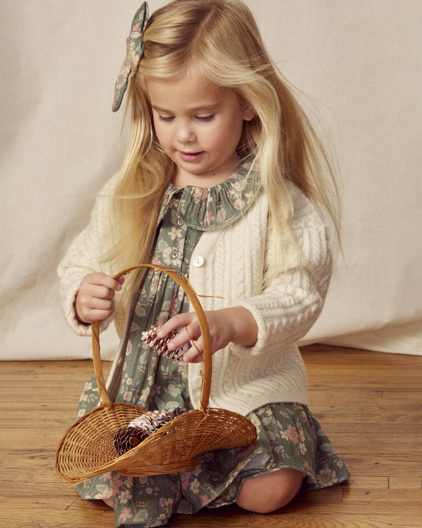Early Sunday, Suzie Dress in Autumn Bloom Soft Green, made from Printed Cotton Double Gauze fabric, featuring classic silhouette with a ruffle neckline and mother-of-pearl buttons, shown in a front view of model wearing it
