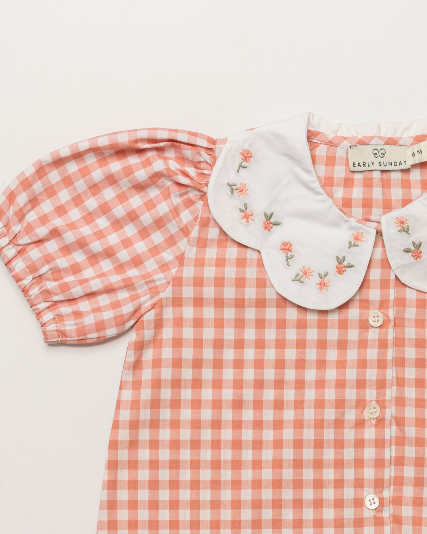 Early Sunday, Tilly Blouse & Holly Baby Shorts Set in Peony color, made from 100% Cotton Gingham Check fabric, featuring a bubble pattern with beautiful embroidery, shown in a closeup flat-lay view