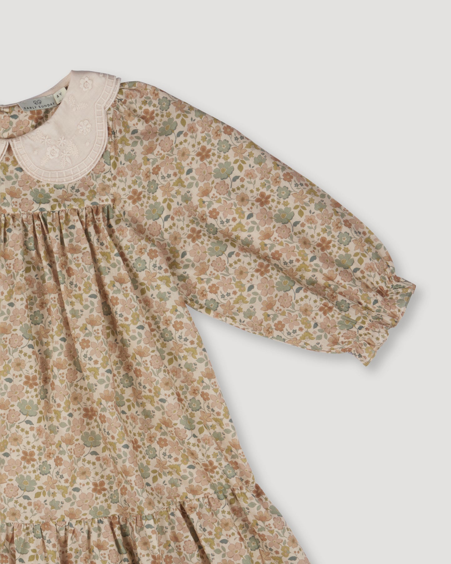 Early Sunday, Virginia Dress in Garden Flowers Cream, made from Printed Cotton Cambric fabric, featuring classic silhouette with embroidered collars, shown in a closeup flat-lay view