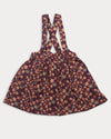 Early Sunday, Annie Skirt in Garden Flowers Plum, made from Printed Cotton Satin fabric, featuring an A-line silhouette with adjustable cross-back straps and soft gathers, shown in a front flat-lay view