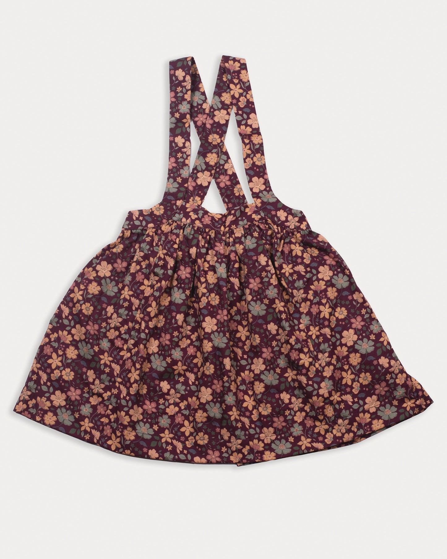 Early Sunday, Annie Skirt in Garden Flowers Plum, made from Printed Cotton Satin fabric, featuring an A-line silhouette with adjustable cross-back straps and soft gathers, shown in a front flat-lay view