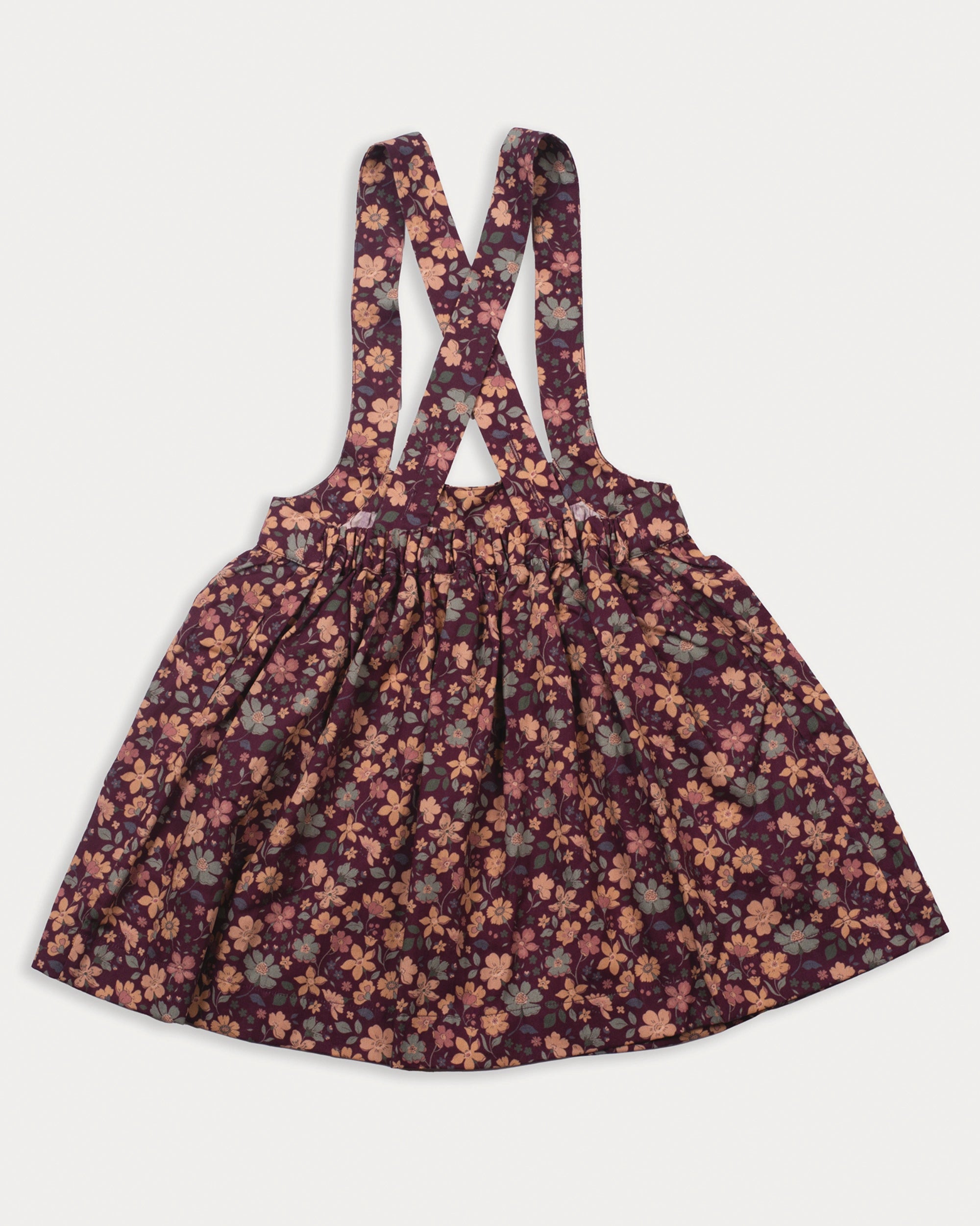 Early Sunday, Annie Skirt in Garden Flowers Plum, made from Printed Cotton Satin fabric, featuring an A-line silhouette with adjustable cross-back straps and soft gathers, shown in a back flat-lay view
