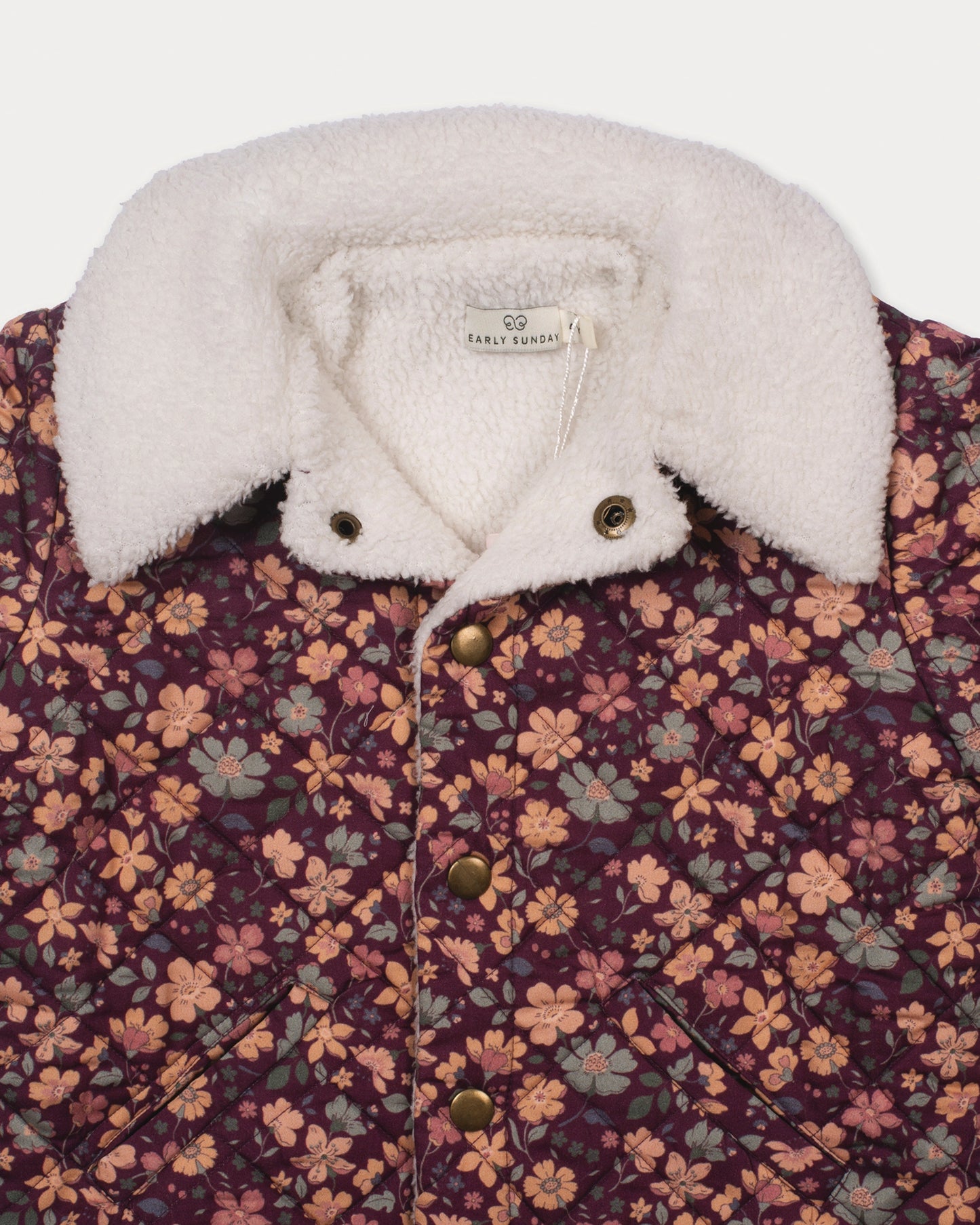 Early Sunday, Esmée Jacket in Garden Flowers Plum, made from Printed Cotton Satin fabric, featuring a quilted layer with delicate floral print and elegant detailing, shown in a closeup flat-lay view