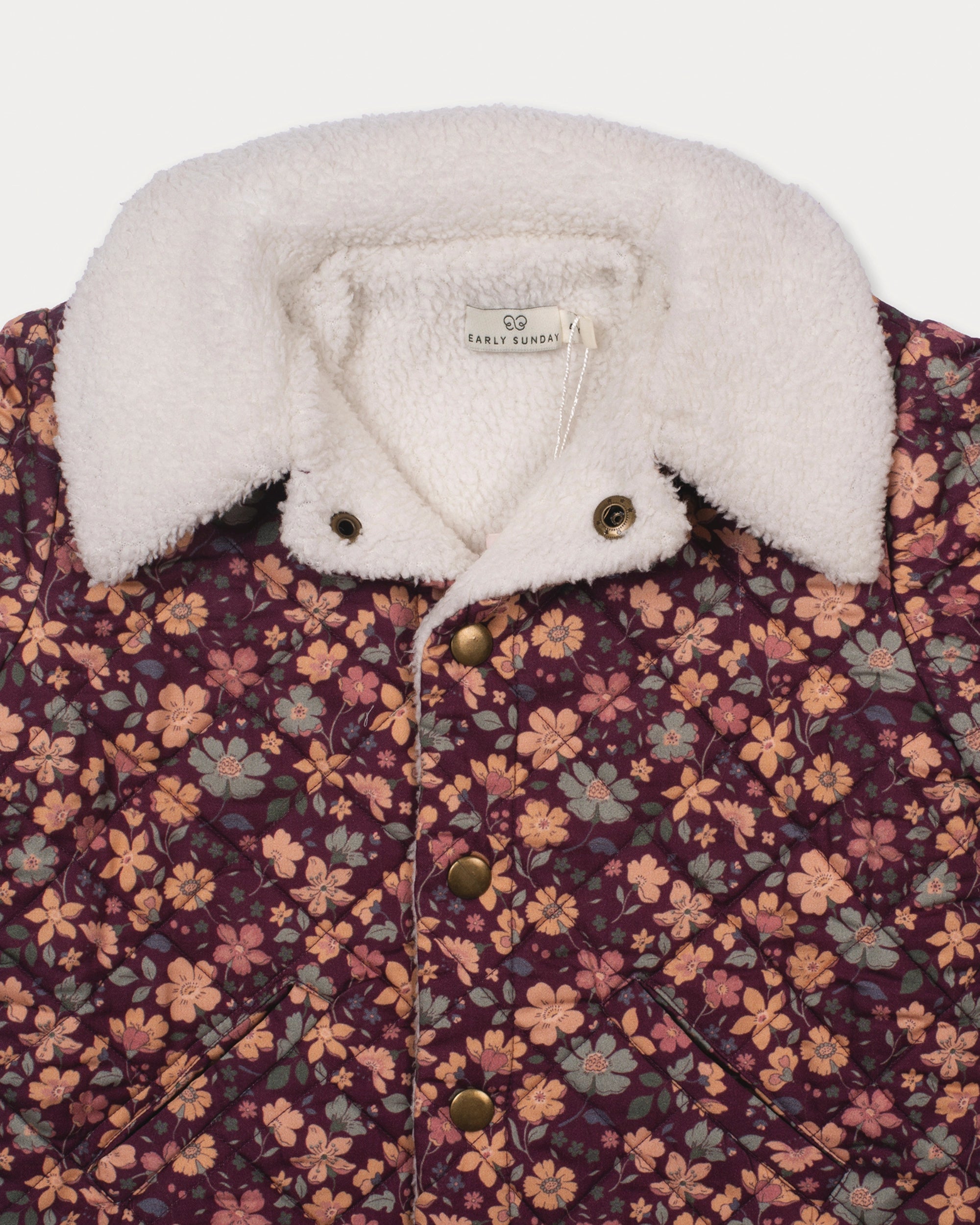 Early Sunday, Esmée Jacket in Garden Flowers Plum, made from Printed Cotton Satin fabric, featuring a quilted layer with delicate floral print and elegant detailing, shown in a closeup flat-lay view