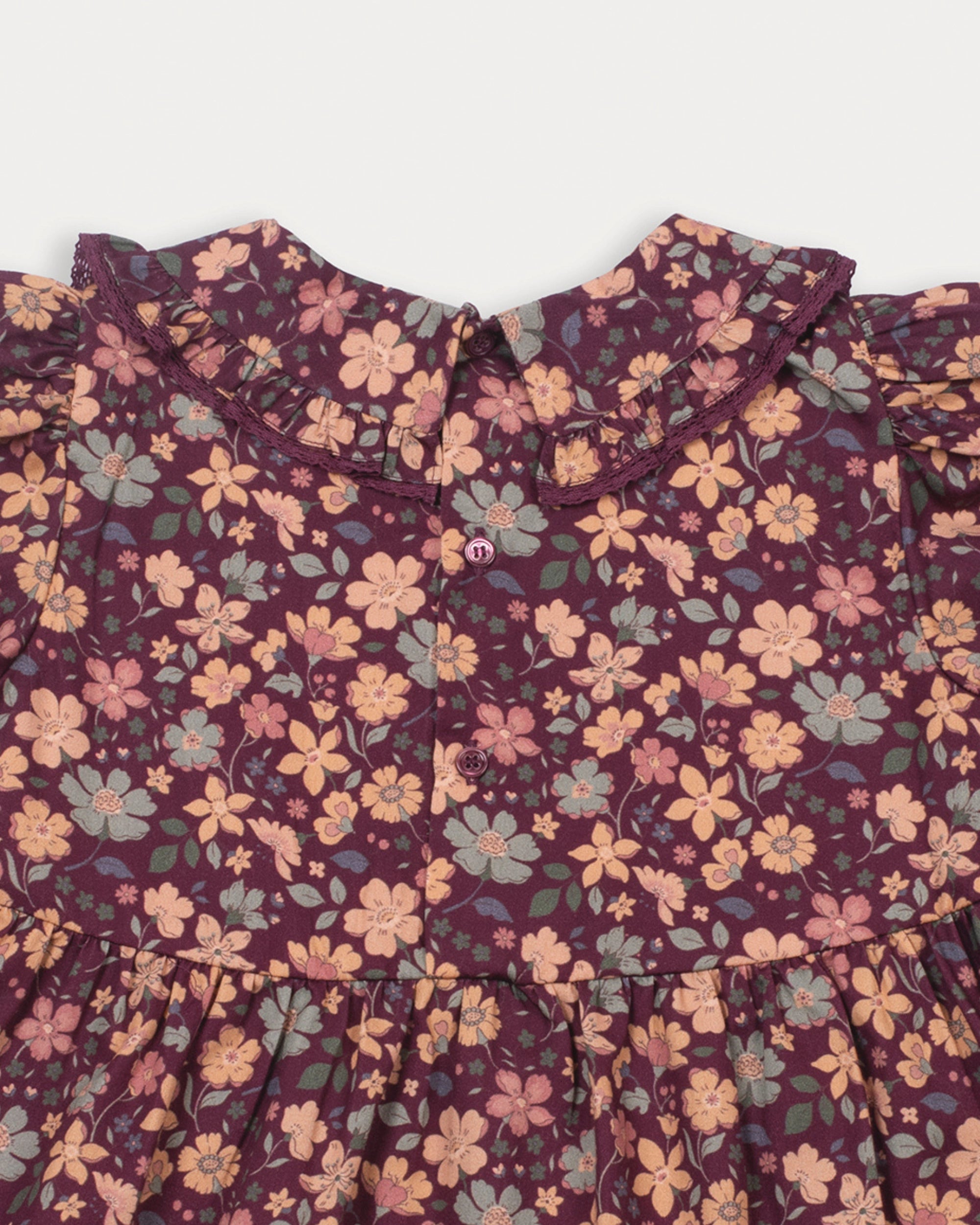 Early Sunday, Marguerite Dress in Garden Flowers Plum, made from Printed Cotton Satin fabric, featuring floral print and detailed lace yoke with Peter Pan collar, shown in a closeup flat-lay view