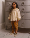 Early Sunday, Adrien Trouser in Almond, made from Dyed Cotton Velvet fabric, featuring Relaxed design with ample room for movement, perfect for active kids, shown in a front view of model wearing it