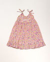 Early Sunday, Alena dress in Emma Floral Purple color, made from organic printed cotton cambric fabric, featuring tie-up shoulder straps, gathered flare, and ruffled hem, shown in a back flat-lay view