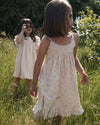 Early Sunday, Alena dress in Painted Bouquet color, made from printed 70% cotton 30% linen fabric, featuring tie-up shoulder straps, gathered flare, and ruffled hem, shown in a front view of model wearing it.