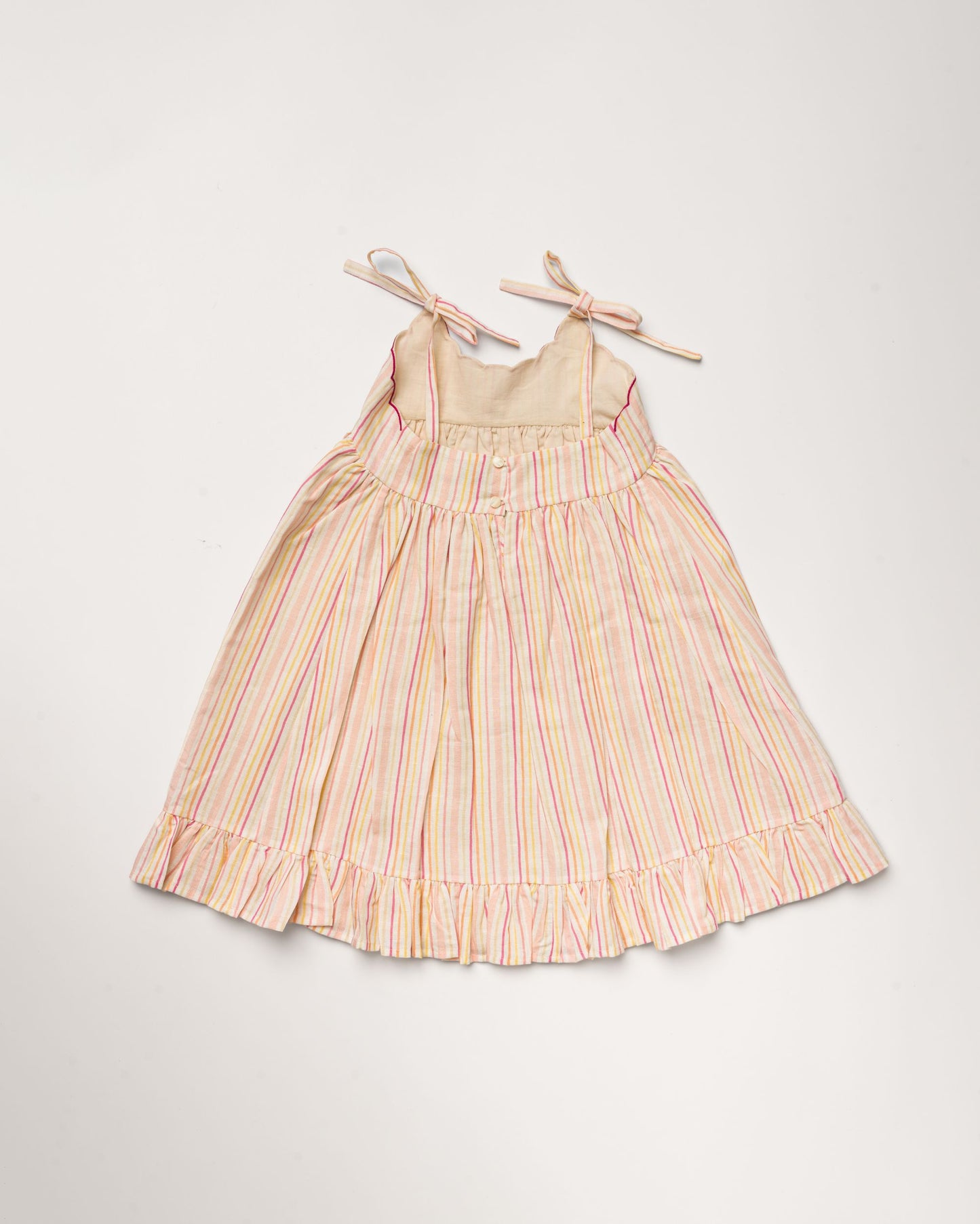 Early Sunday, Alena dress in Pink Stripes color, made from printed 70% cotton 30% linen fabric, featuring tie-up shoulder straps, gathered flare, and ruffled hem, shown in a back flat-lay view.