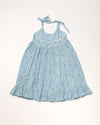 Early Sunday, Alena dress in Tonal Floral Blue color, made from printed cotton tiny swiss dobby fabric, featuring tie-up shoulder straps, gathered flare, and ruffled hem, shown in a back flat-lay view.