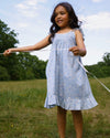 Early Sunday, Alena dress in Tonal Floral Blue color, made from printed cotton tiny swiss dobby fabric, featuring tie-up shoulder straps, gathered flare, and ruffled hem, shown in a model in motion.