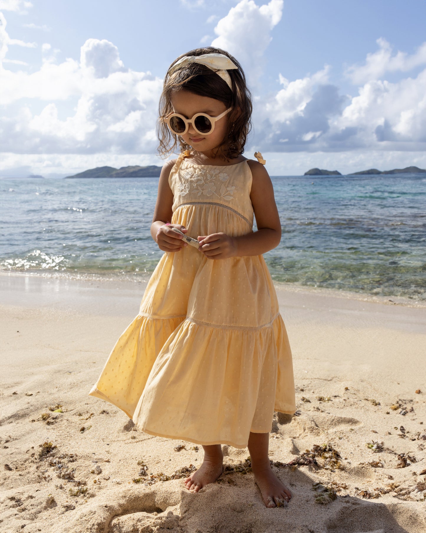 Early Sunday, Alice Dress in Vanilla, made from Cotton Dobby Swiss Dots fabric, featuring sleeveless with adjustable tie-up straps and a tiered silhouette, shown in a front view of model wearing it
